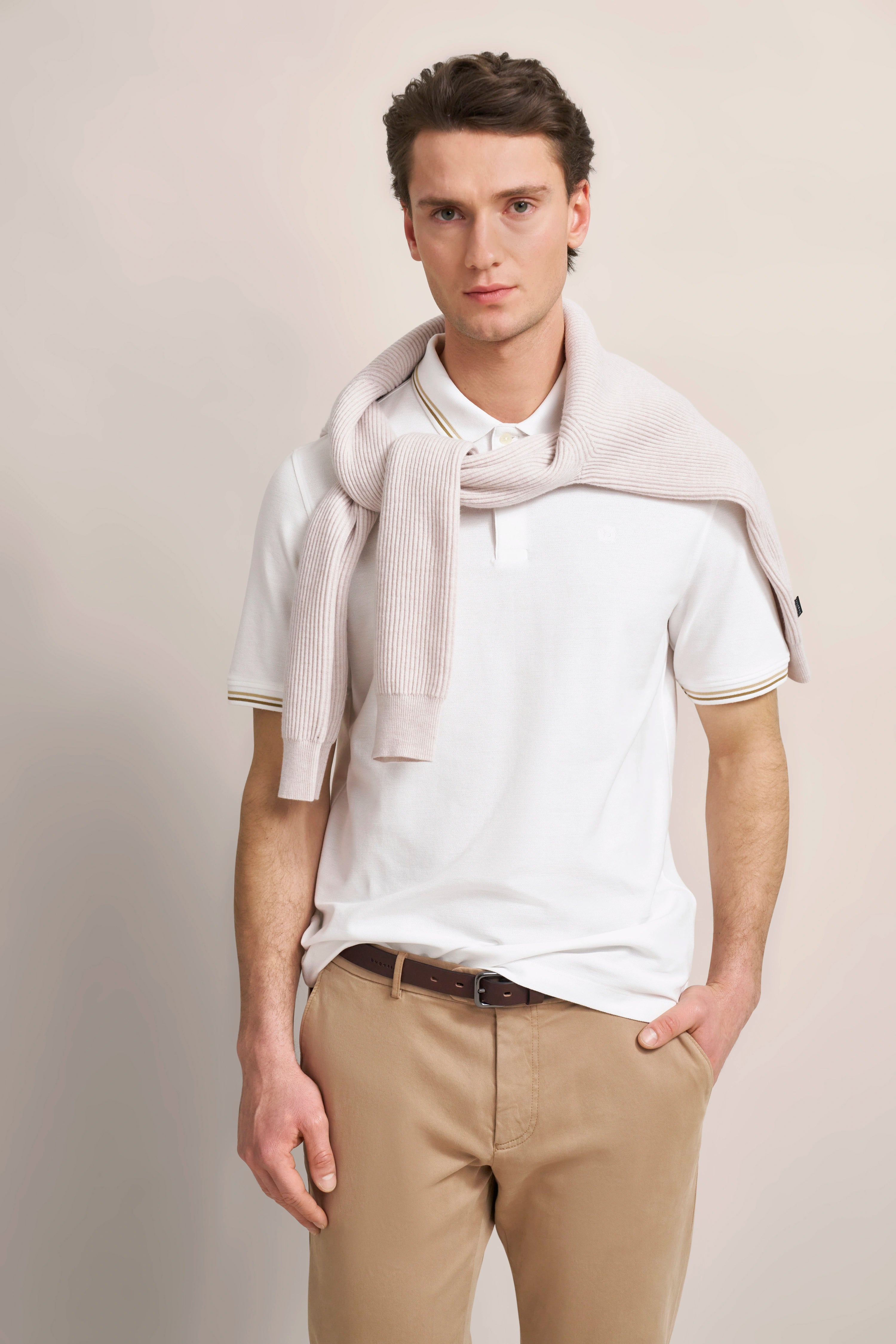 Weißes Polo, beiger Pulli und Hose, legeres Posing, bugatti Stil.