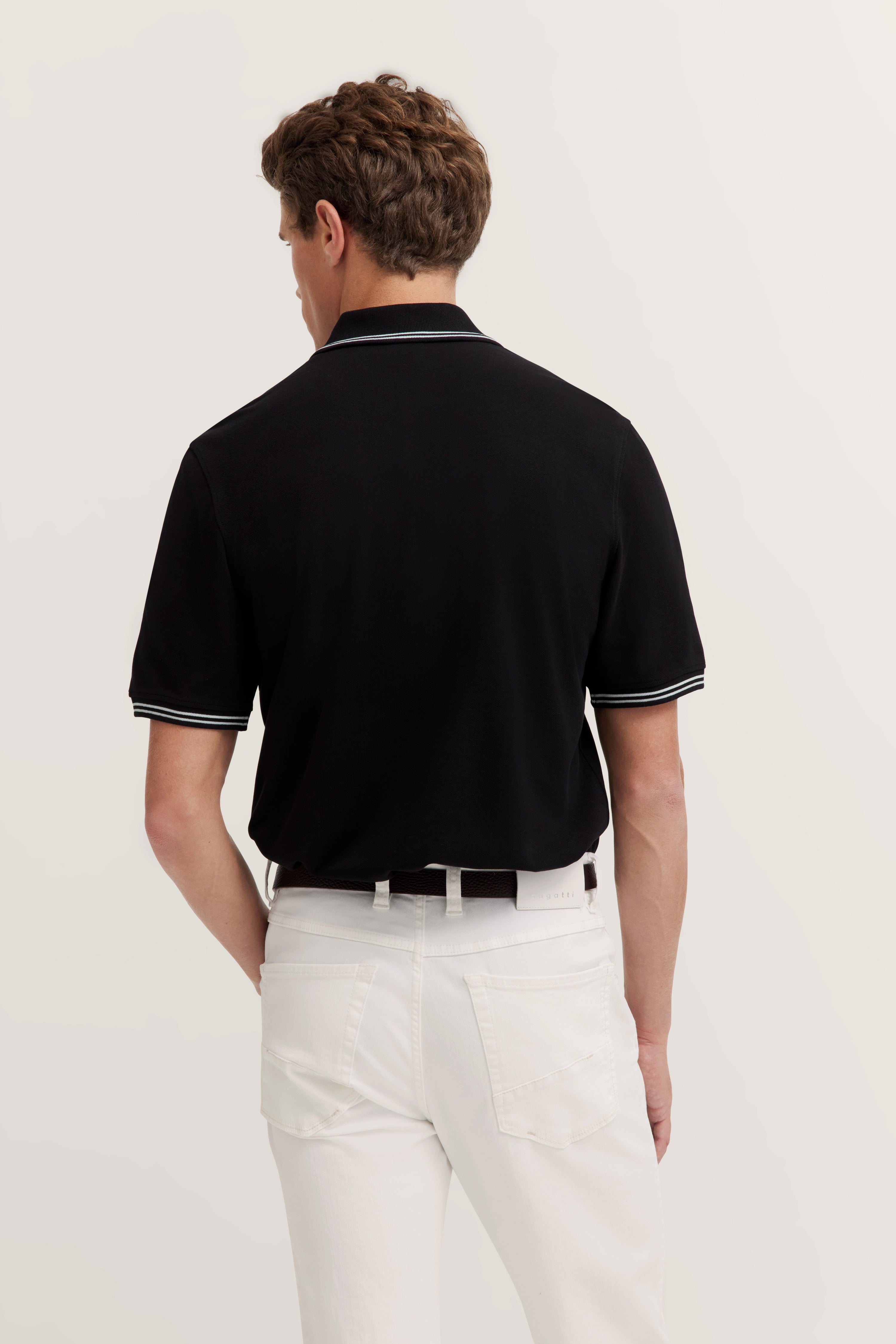 Zwart poloshirt met witte strepen, witte broek, achterkant, model staat ontspannen.