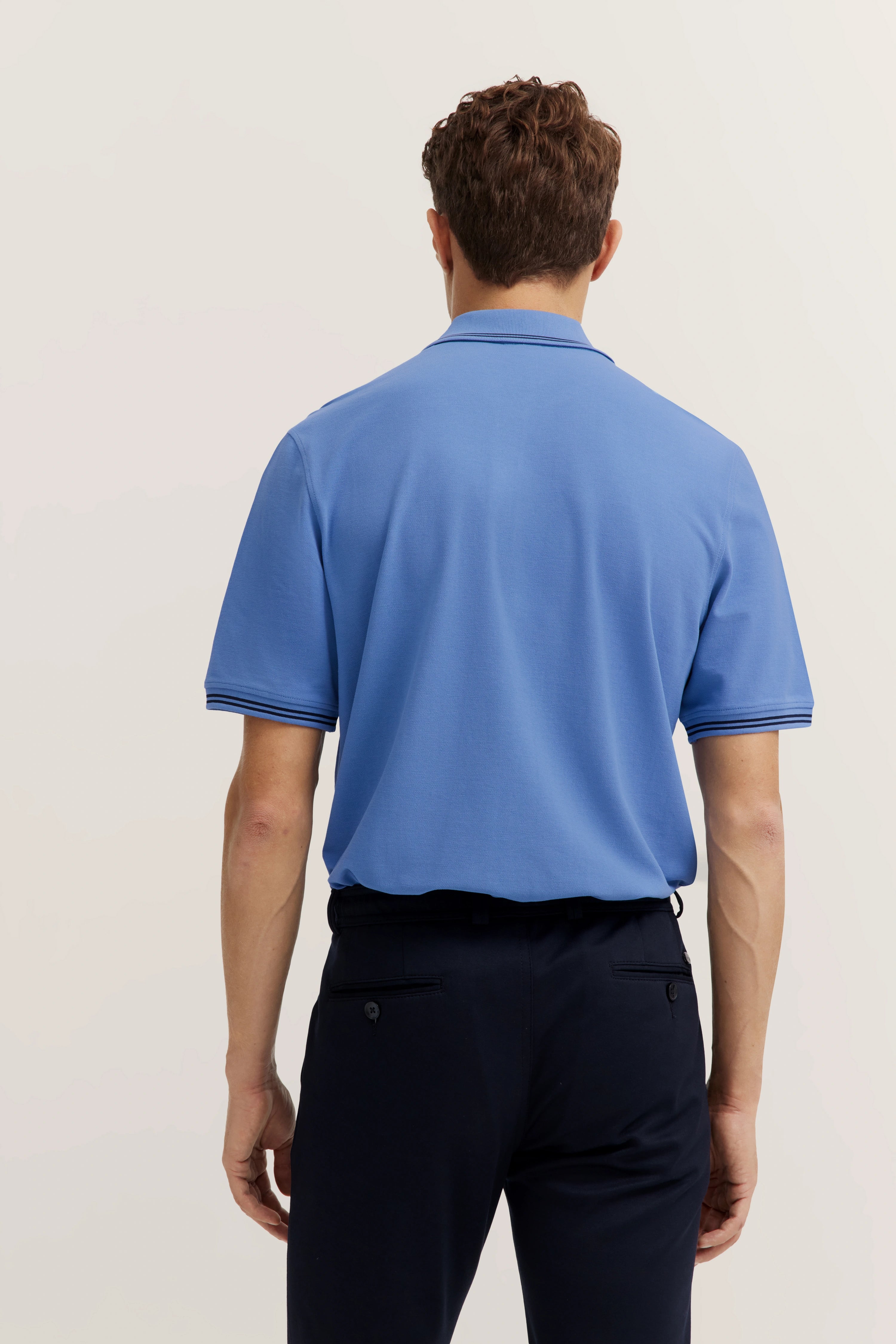 Blue bugatti polo shirt and dark pants, back view, casual outfit.