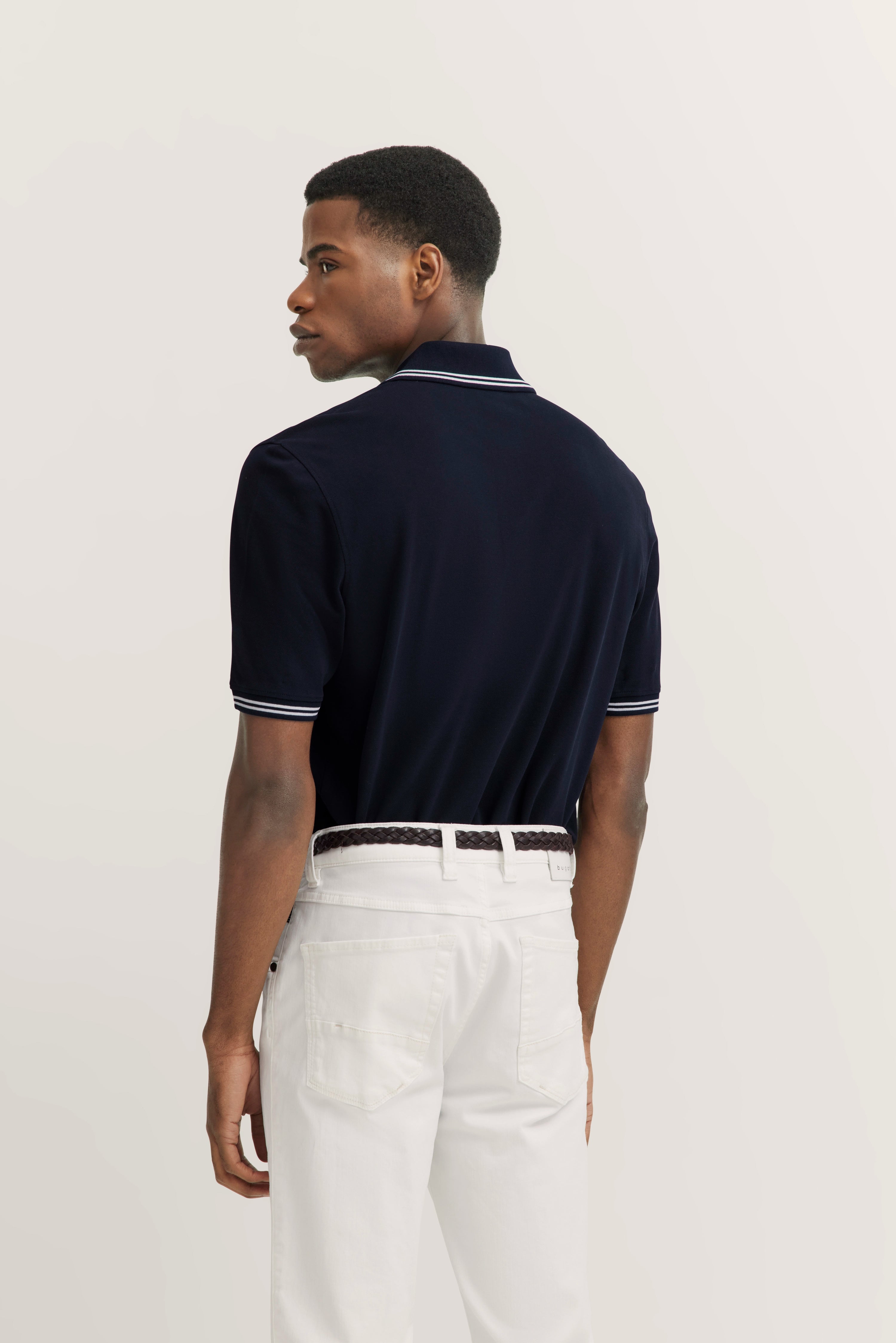 Navy Polo und weiße Hose, Model von hinten, lässige Pose, bugatti Stil.