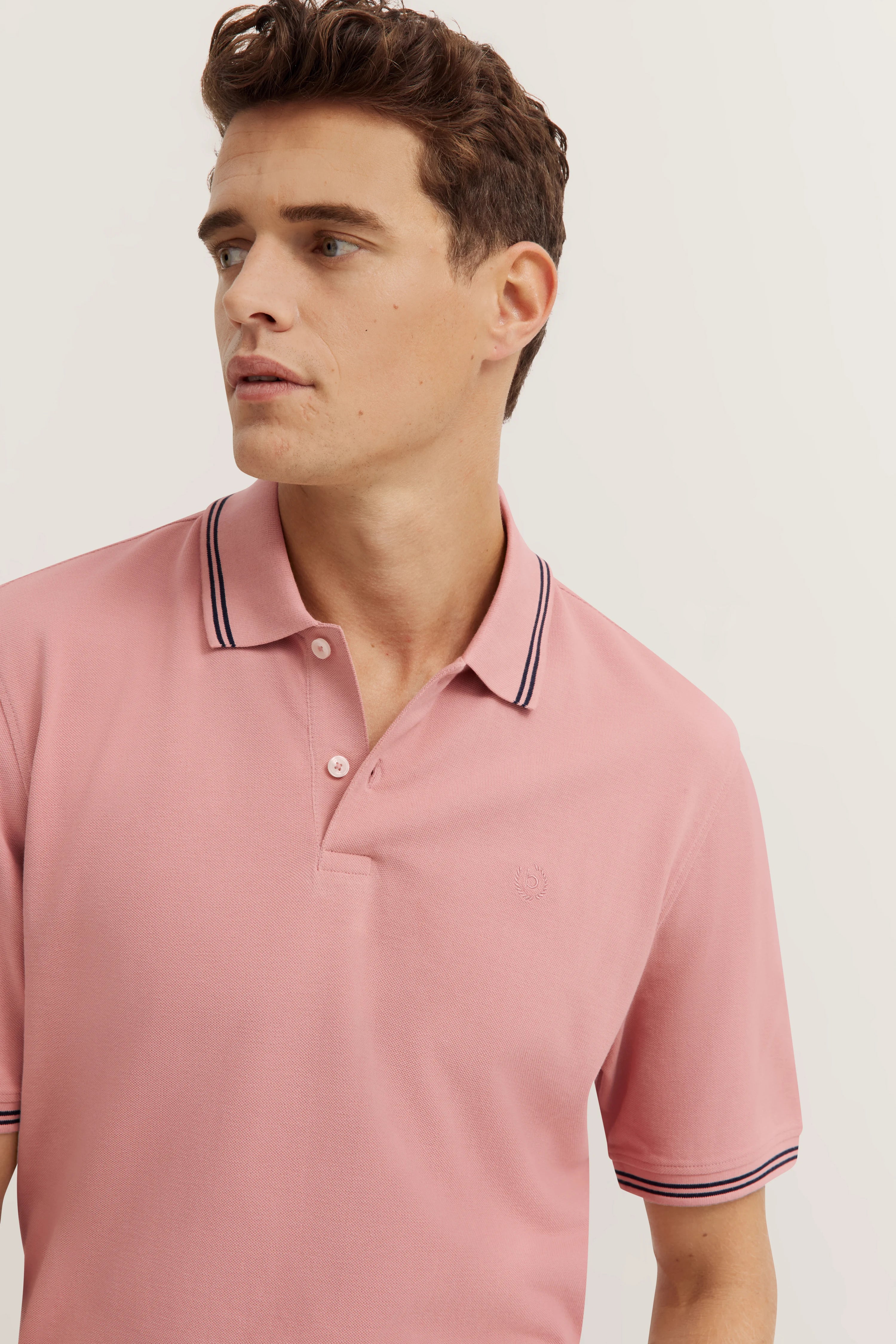 Polohemd in Rosa mit Kontraststreifen, Modelbild, Kopf zur Seite gewandt.