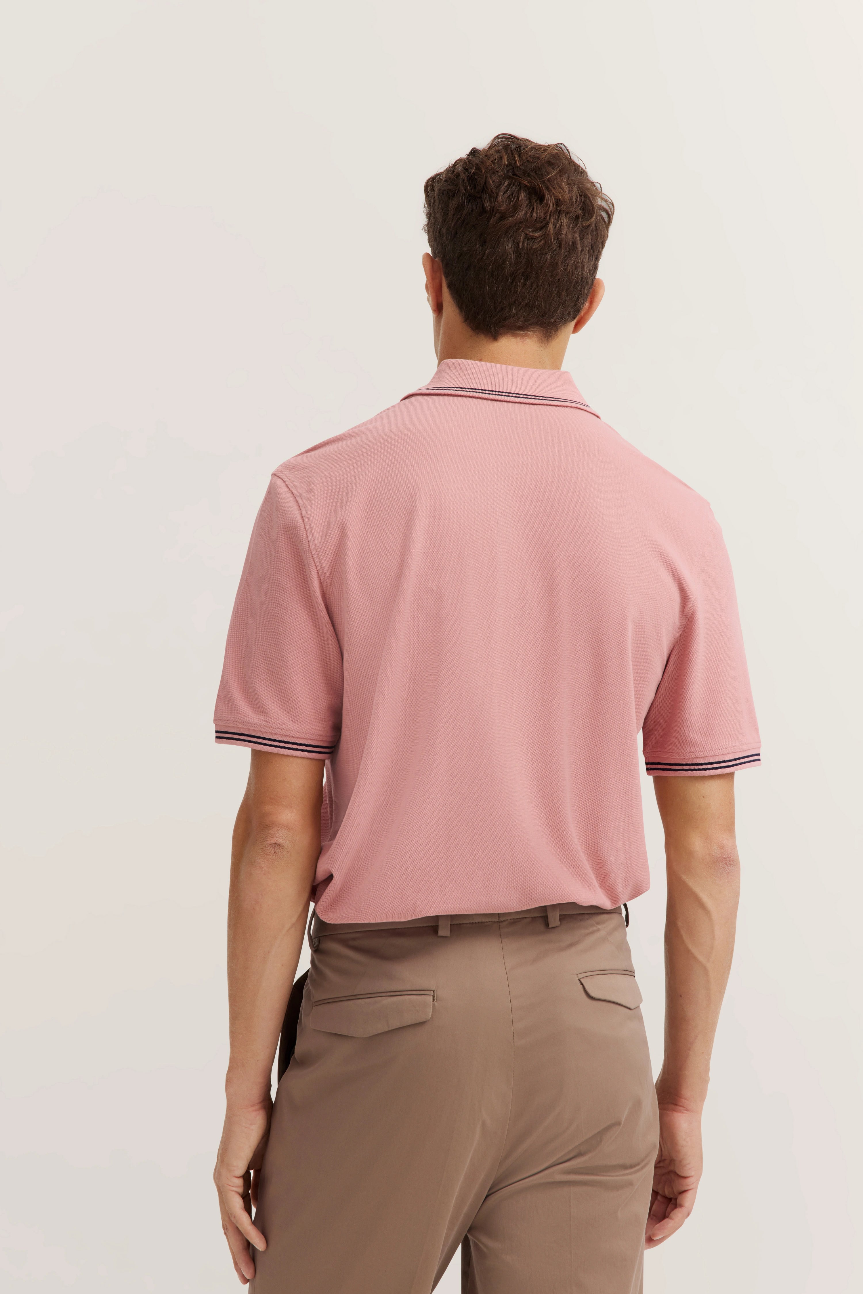 Rückenansicht Model in rosa bugatti Polo und beige Hose, legeres Outfit.
