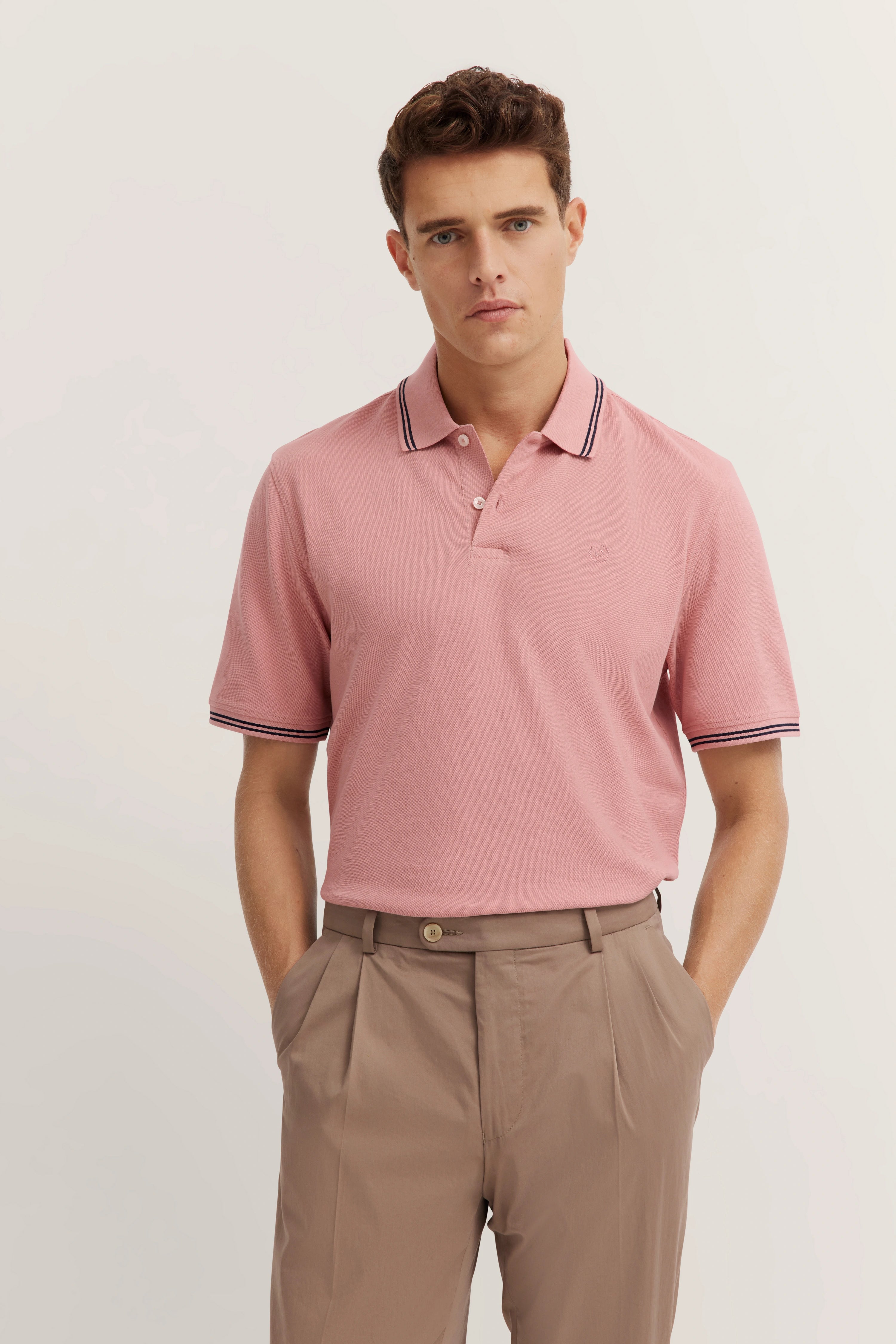 bugatti model: man in pink polo shirt and beige pants, relaxed pose, timeless elegance.