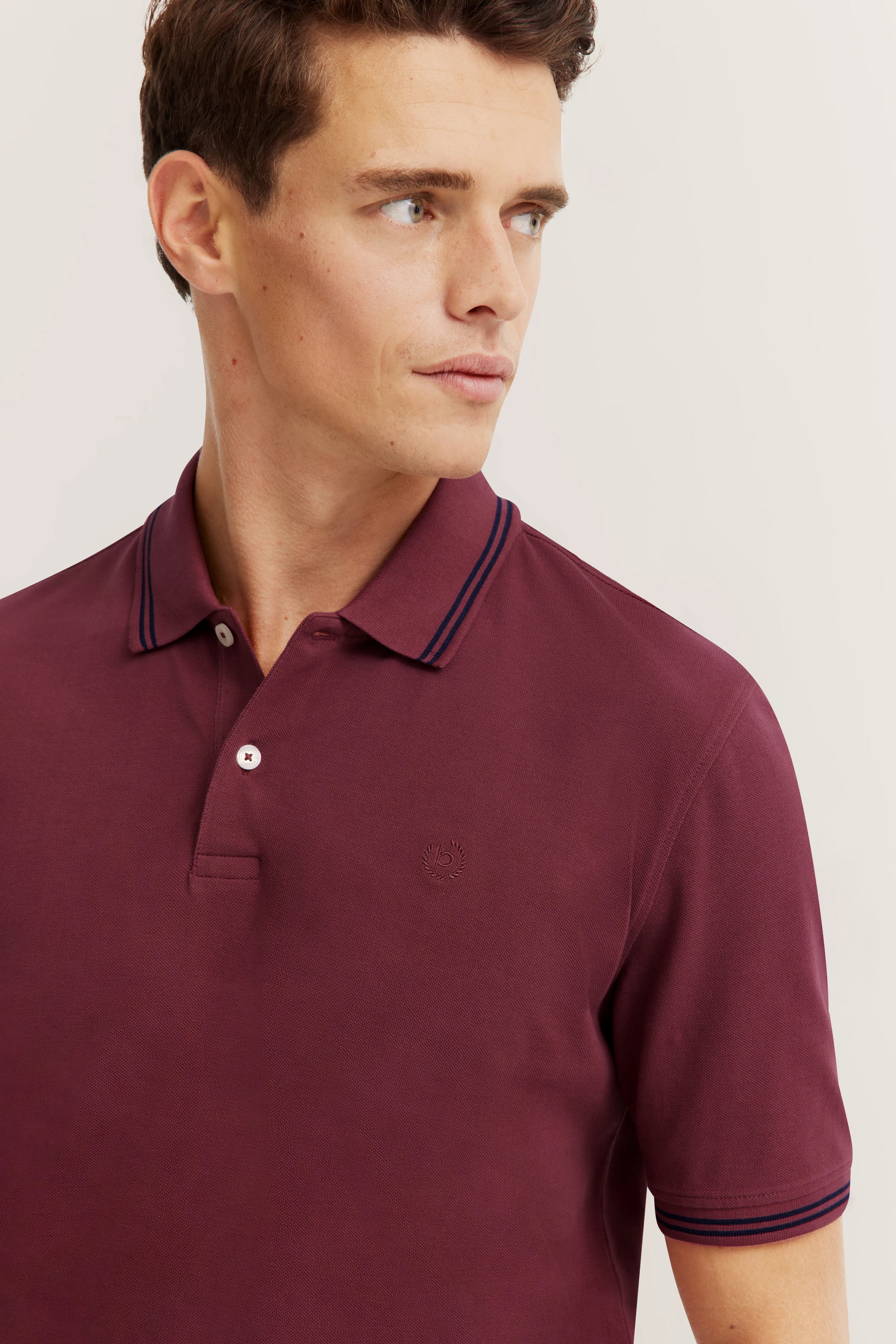 Bordeauxfarbenes bugatti Poloshirt auf Model, legeres Portrait, entspanntes Posing.