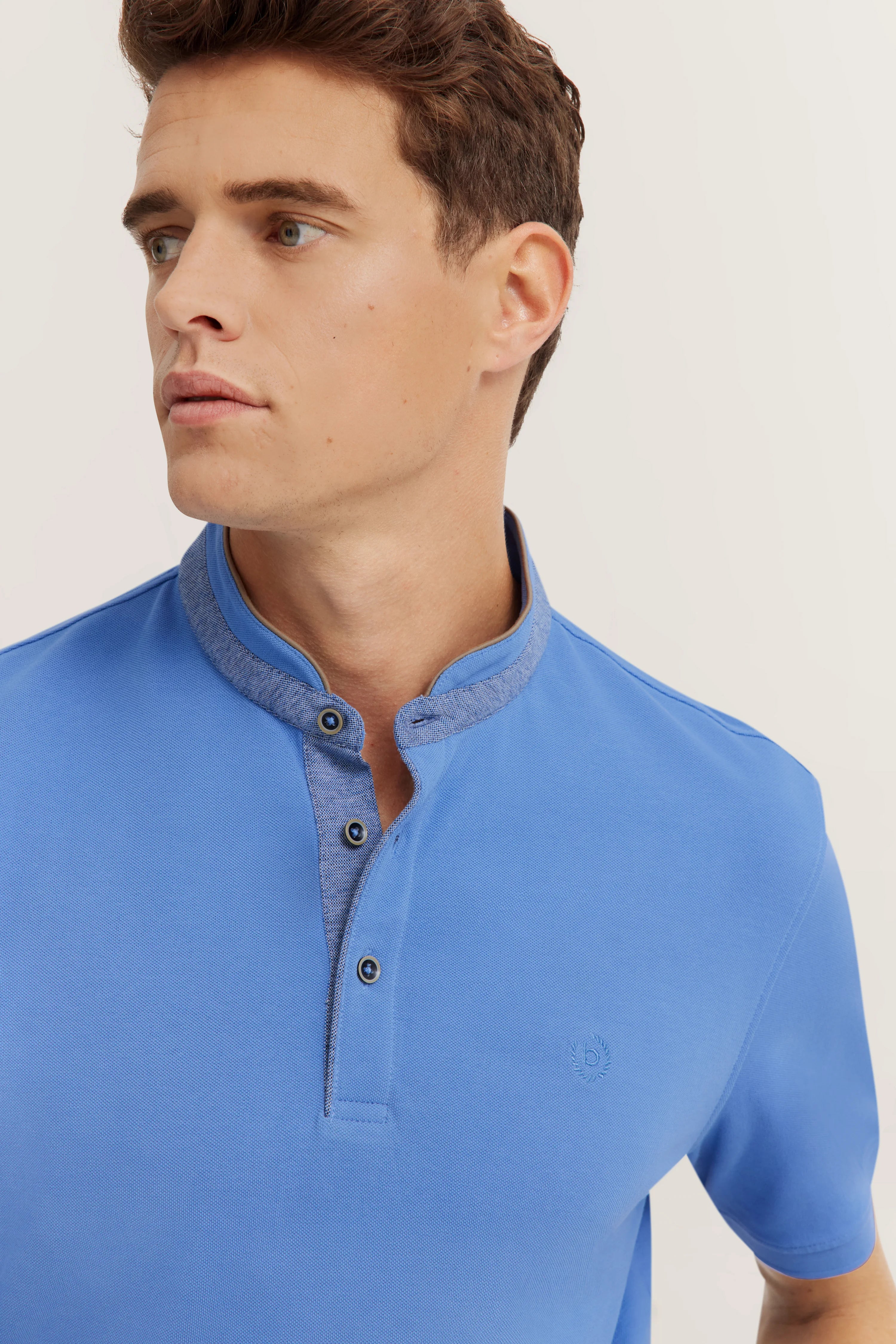 Blue bugatti polo shirt with stand-up collar, model image, casual look, head turned sideways.