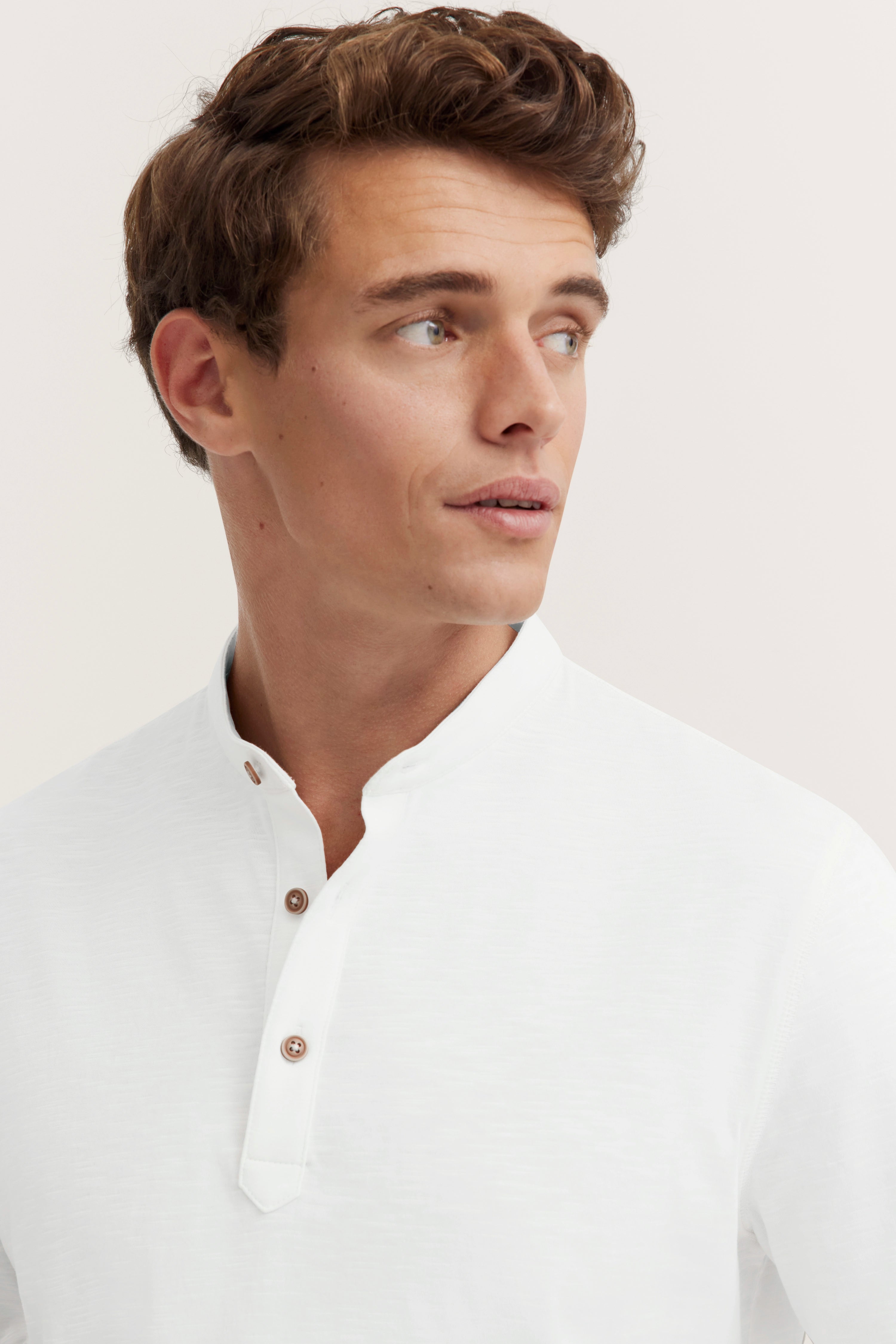 White bugatti shirt with stand-up collar and button placket, model looking relaxed to the right.