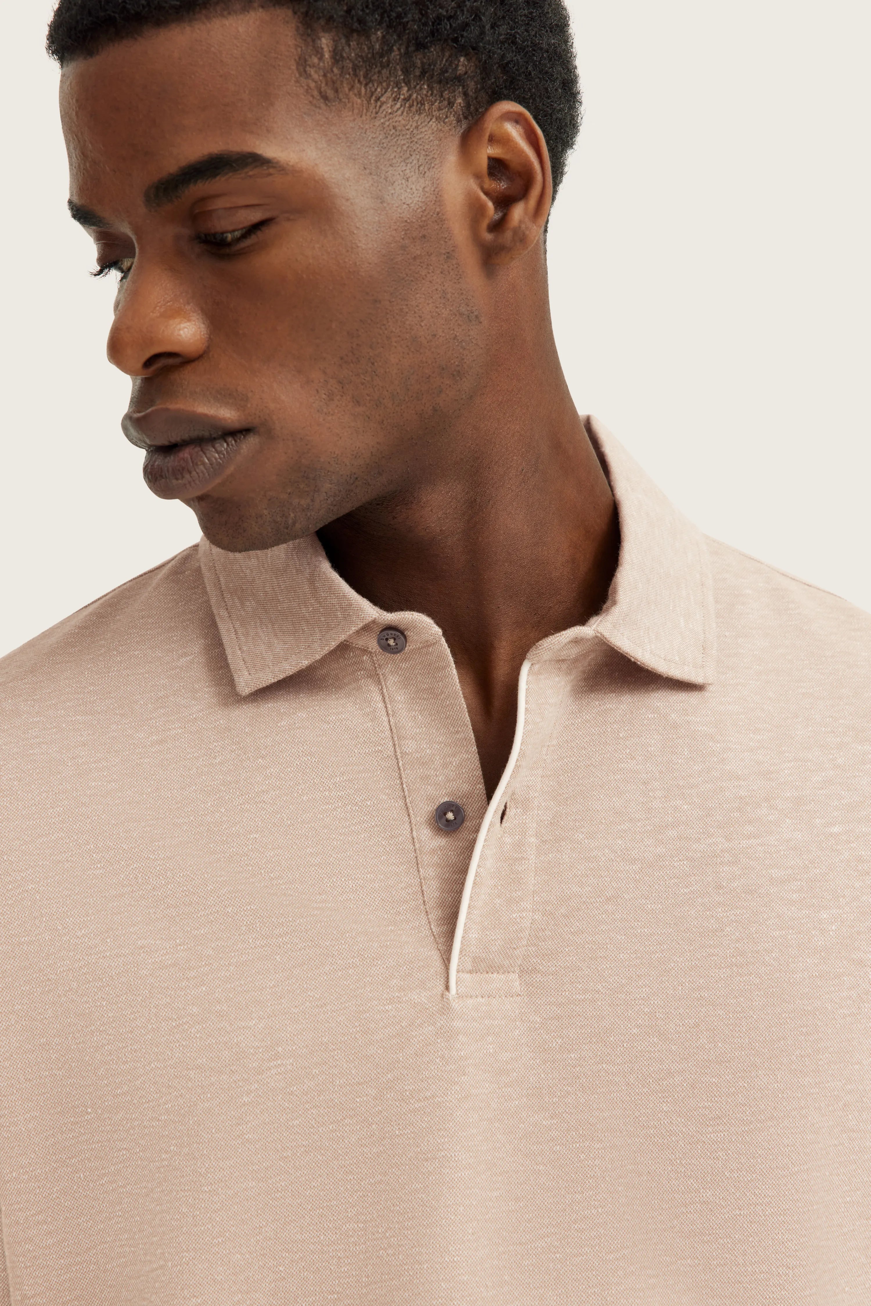Beiges bugatti Poloshirt aus Baumwolle, Modelbild, lässige Pose, Fokus auf Kragen und Textur.