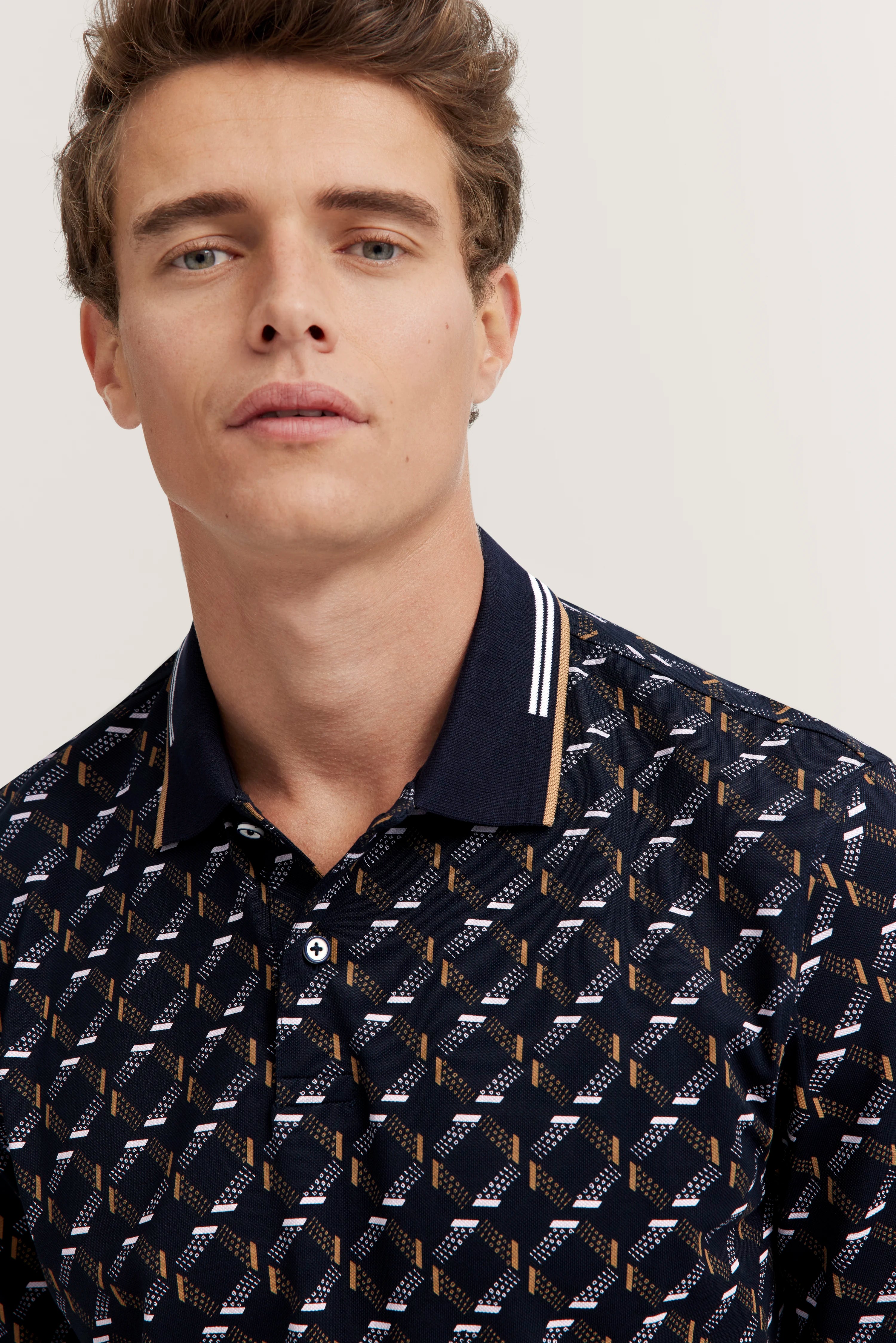 Model wearing patterned dark blue polo shirt, close-up, casual design, style by bugatti.