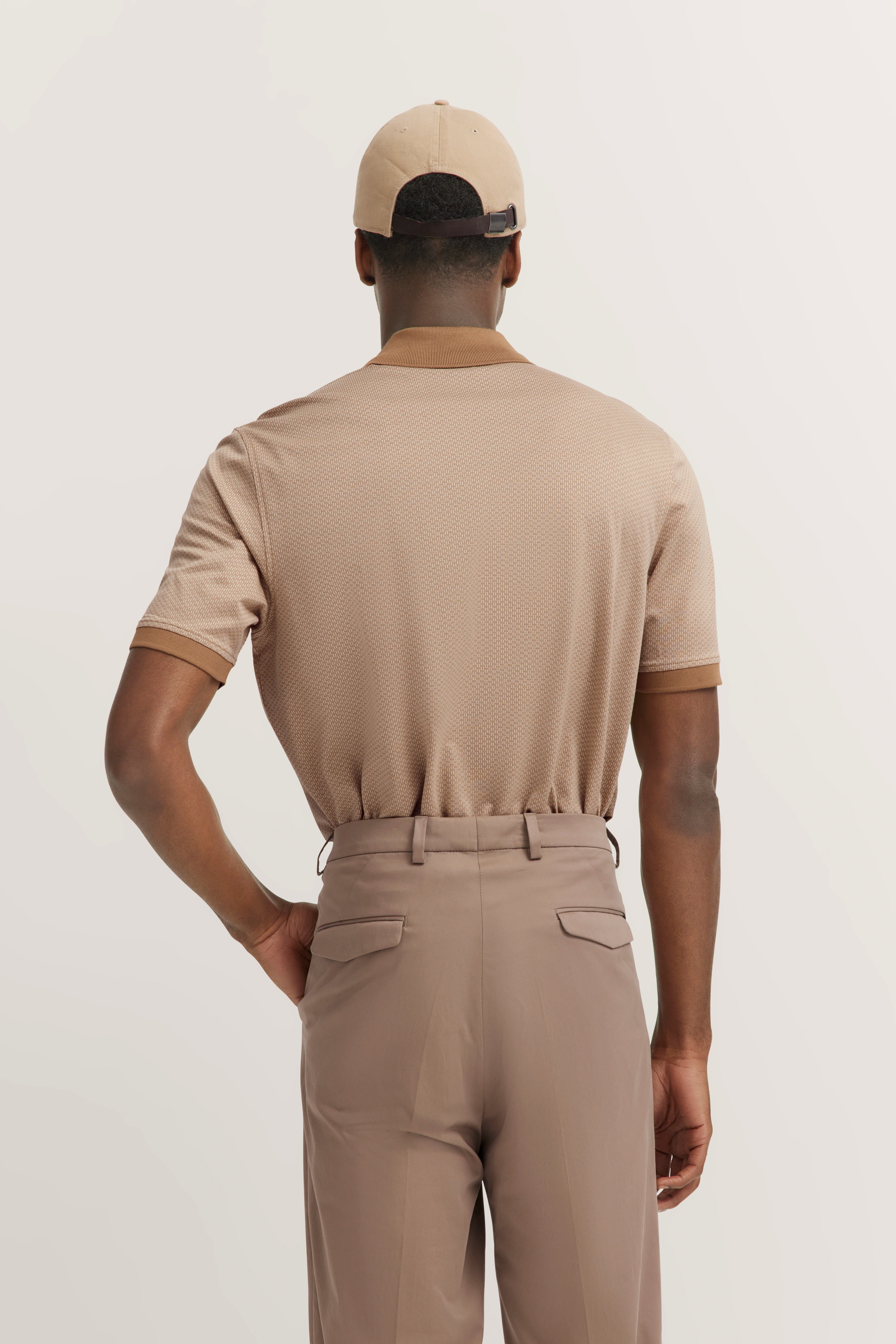 Beige outfit with polo shirt and pants, rear model view, relaxed posture.