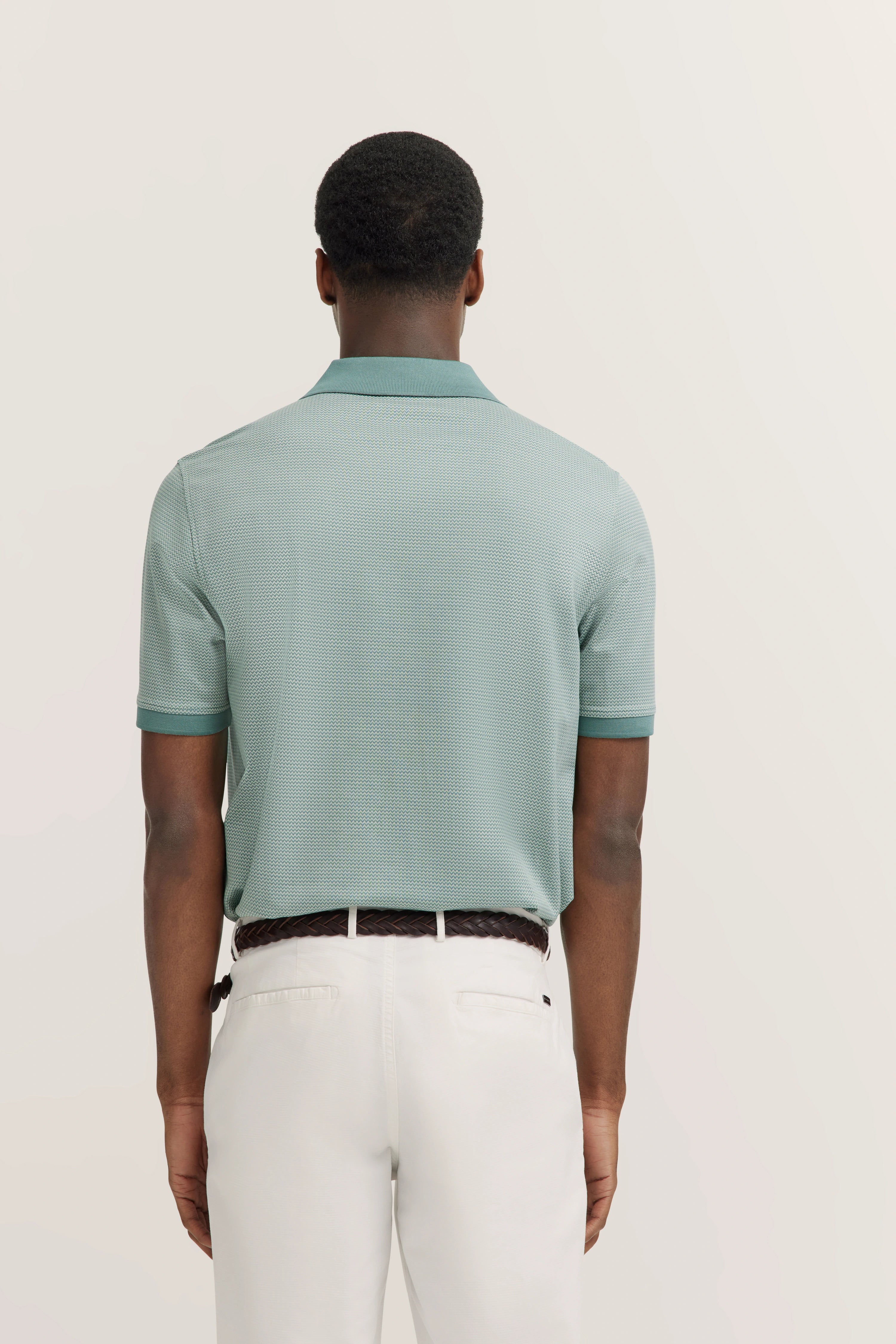 Man from behind in mint green polo shirt and white trousers, exuding bugatti's timeless elegance and Italian-inspired style.