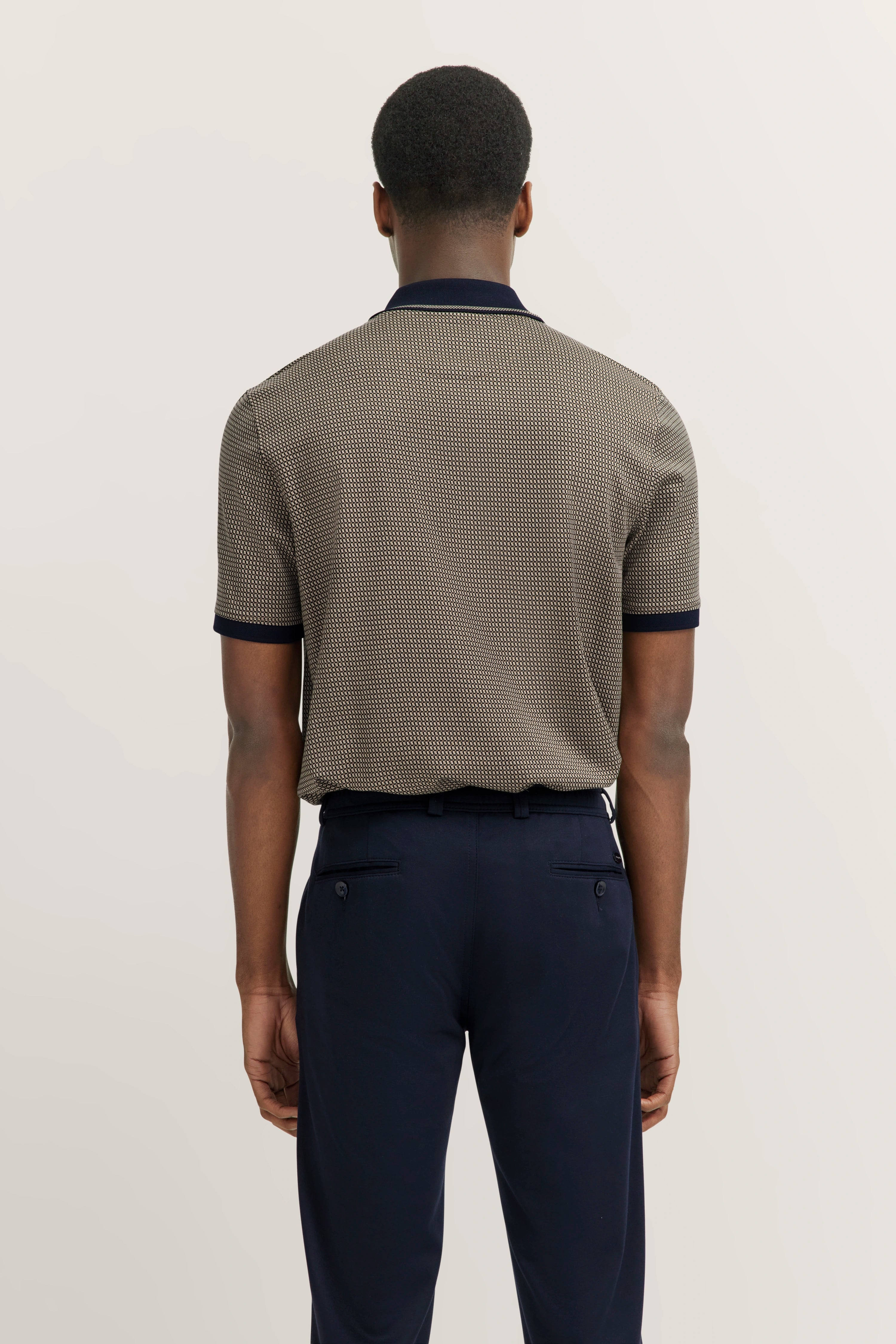 Poloshirt beige mit Muster, Navy-Details, kombiniert mit dunkelblauer Hose, Rückansicht, entspannt.