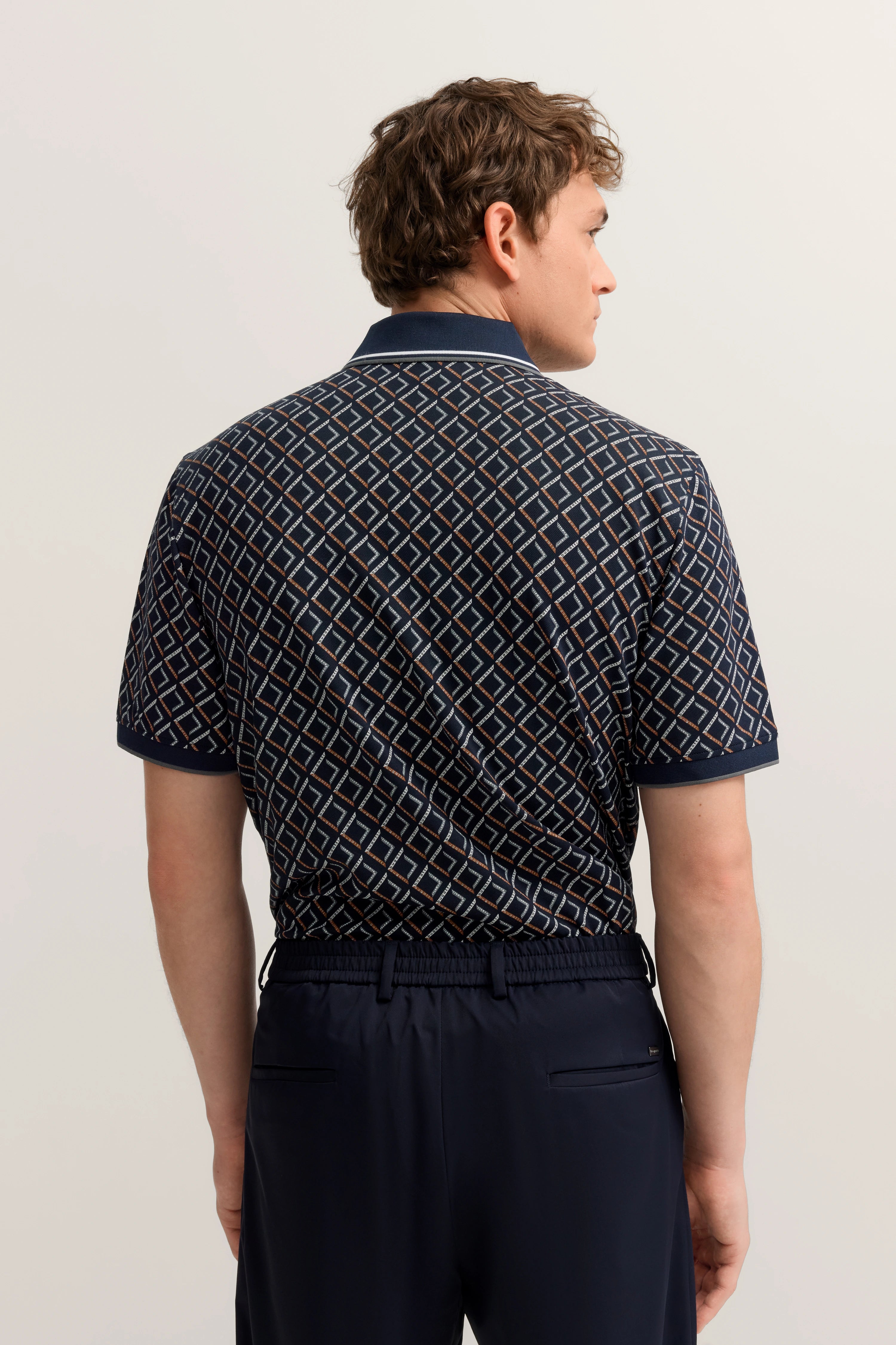 Dunkelblaues gemustertes Polo von bugatti, Modellbild von hinten, entspannte Pose.