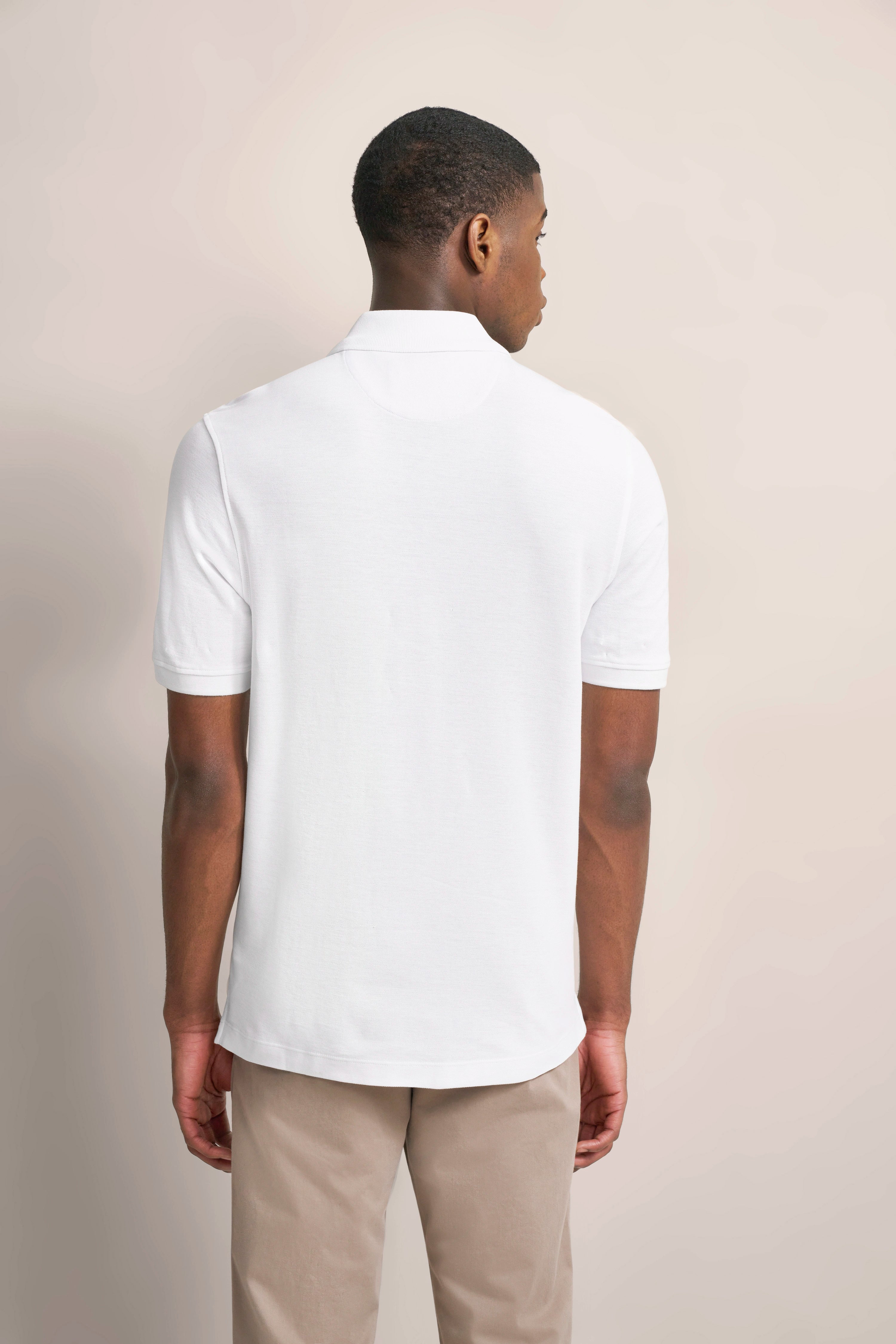 Rear view of model in white polo and beige chinos by bugatti, simple, casual outfit.