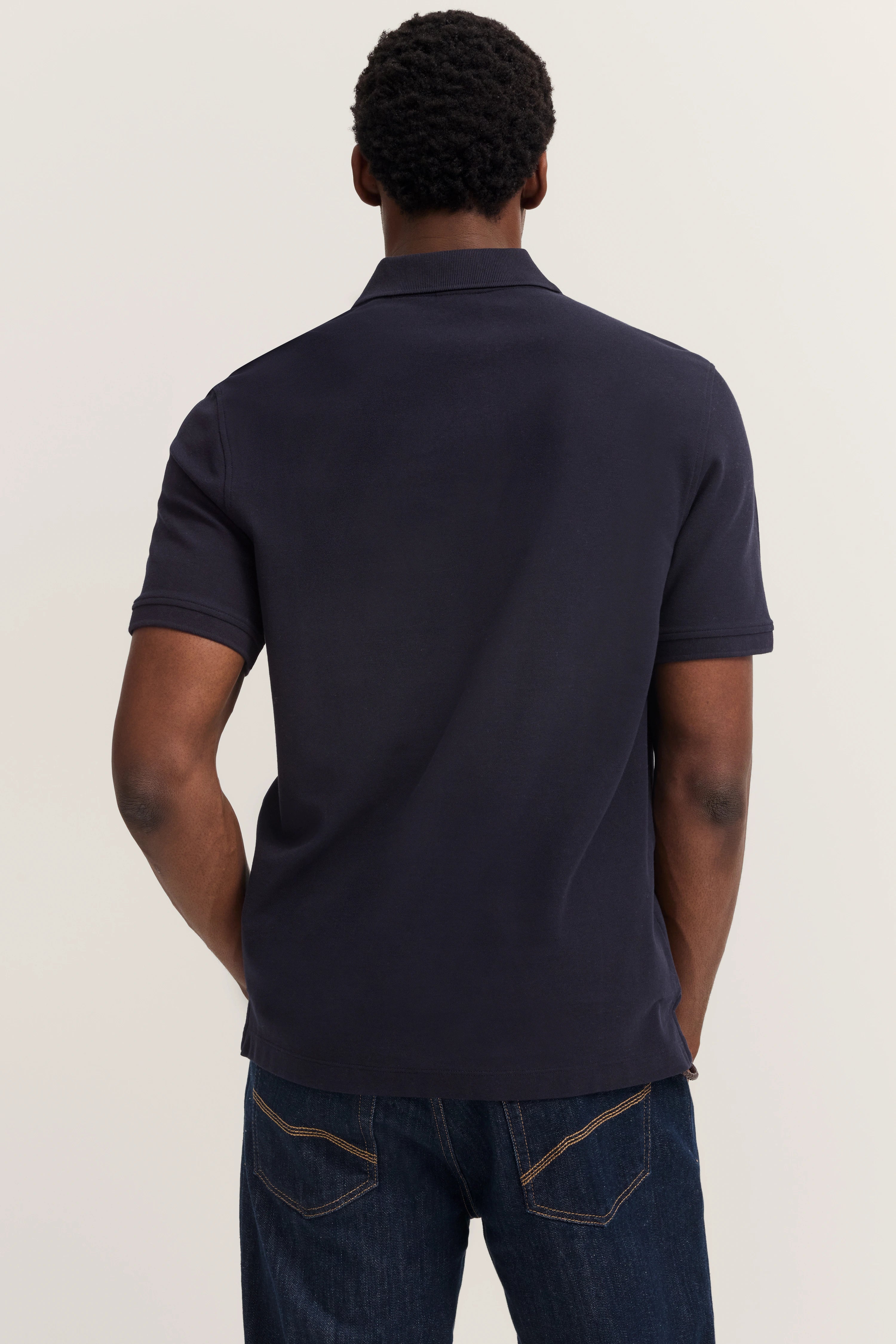Navy Polo-Shirt von bugatti, Rückansicht, lässiges Modelbild, kombiniert mit dunkelblauer Jeans.
