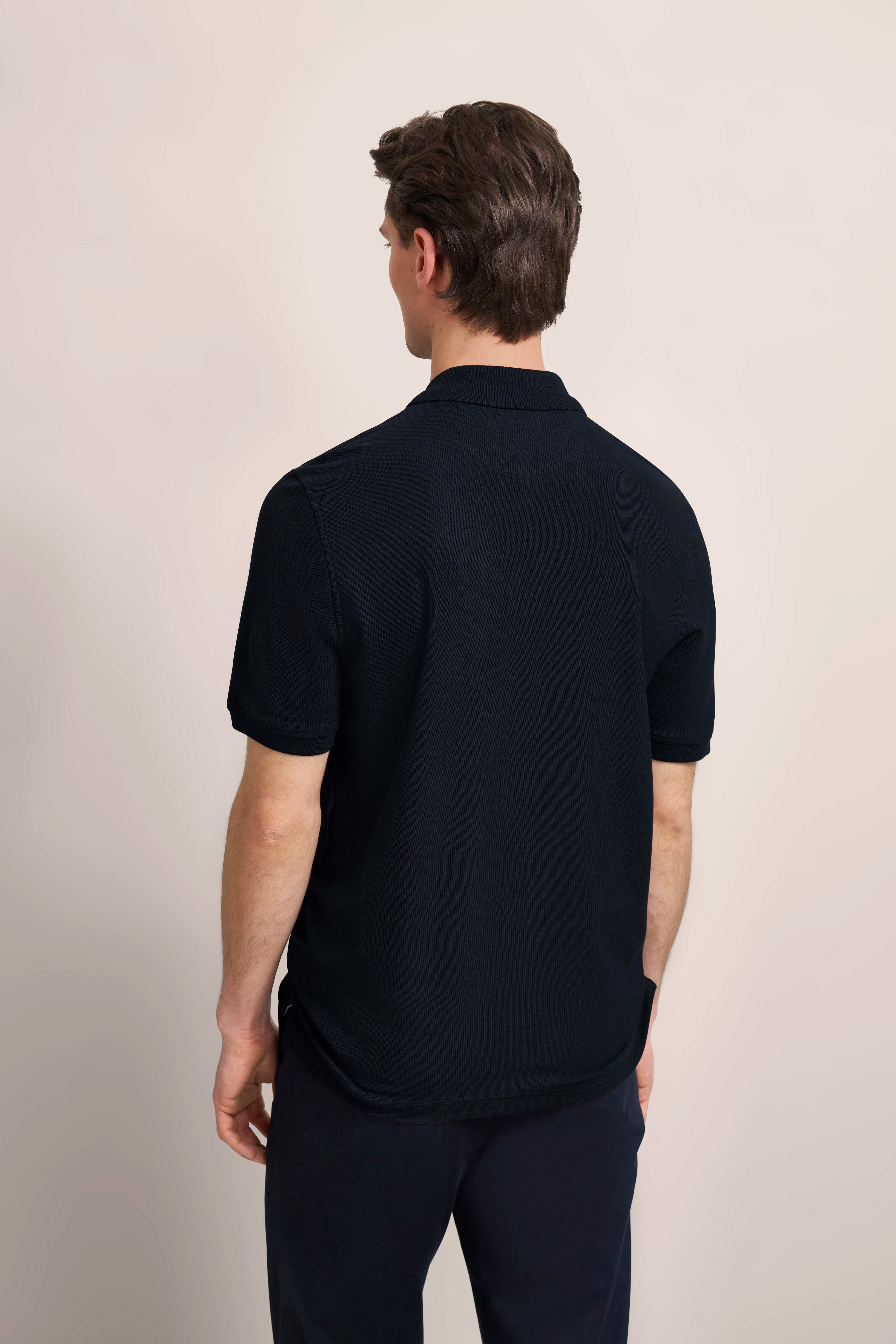 bugatti poloshirt in donkerblauw, achteraanzicht, ontspannen pose.