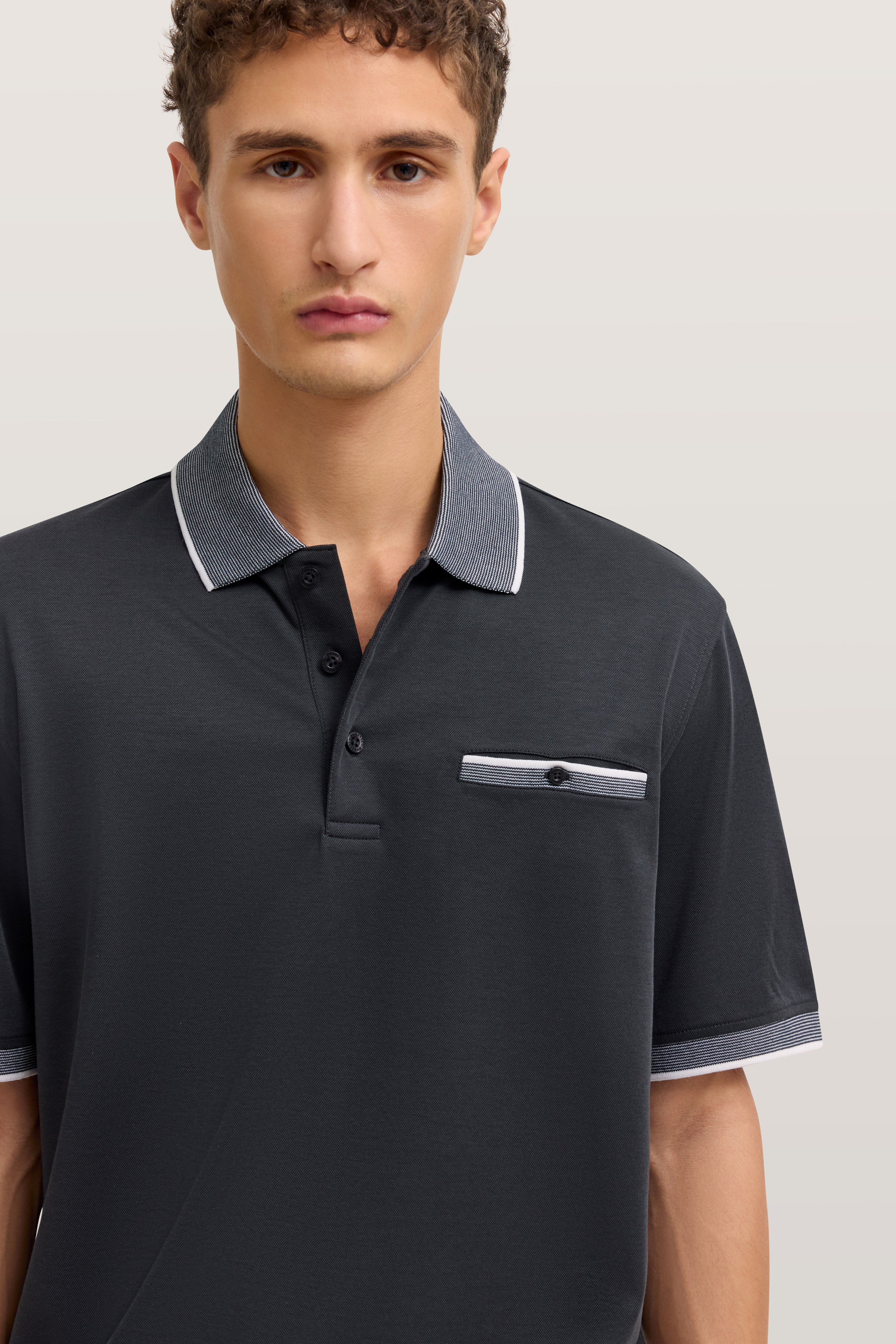 Büstenbild eines Mannes im schwarzen bugatti Poloshirt mit grauem Kragen und Brusttasche.