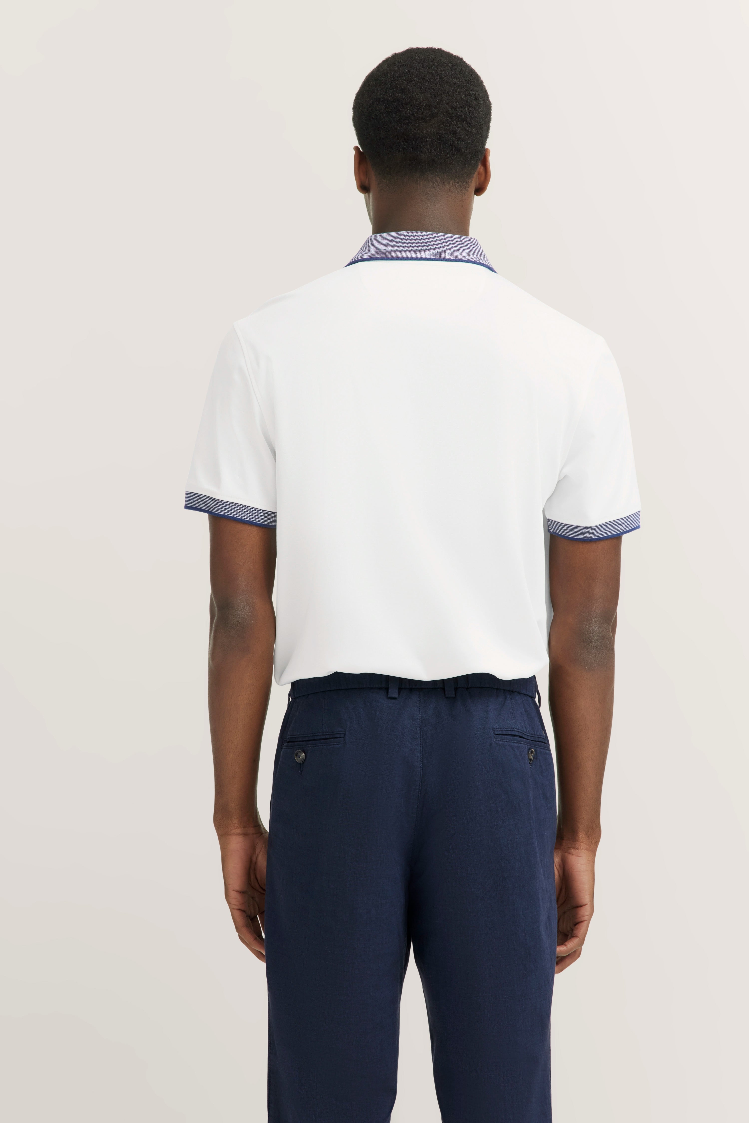 White polo shirt and dark blue pants, back view, casual model image.