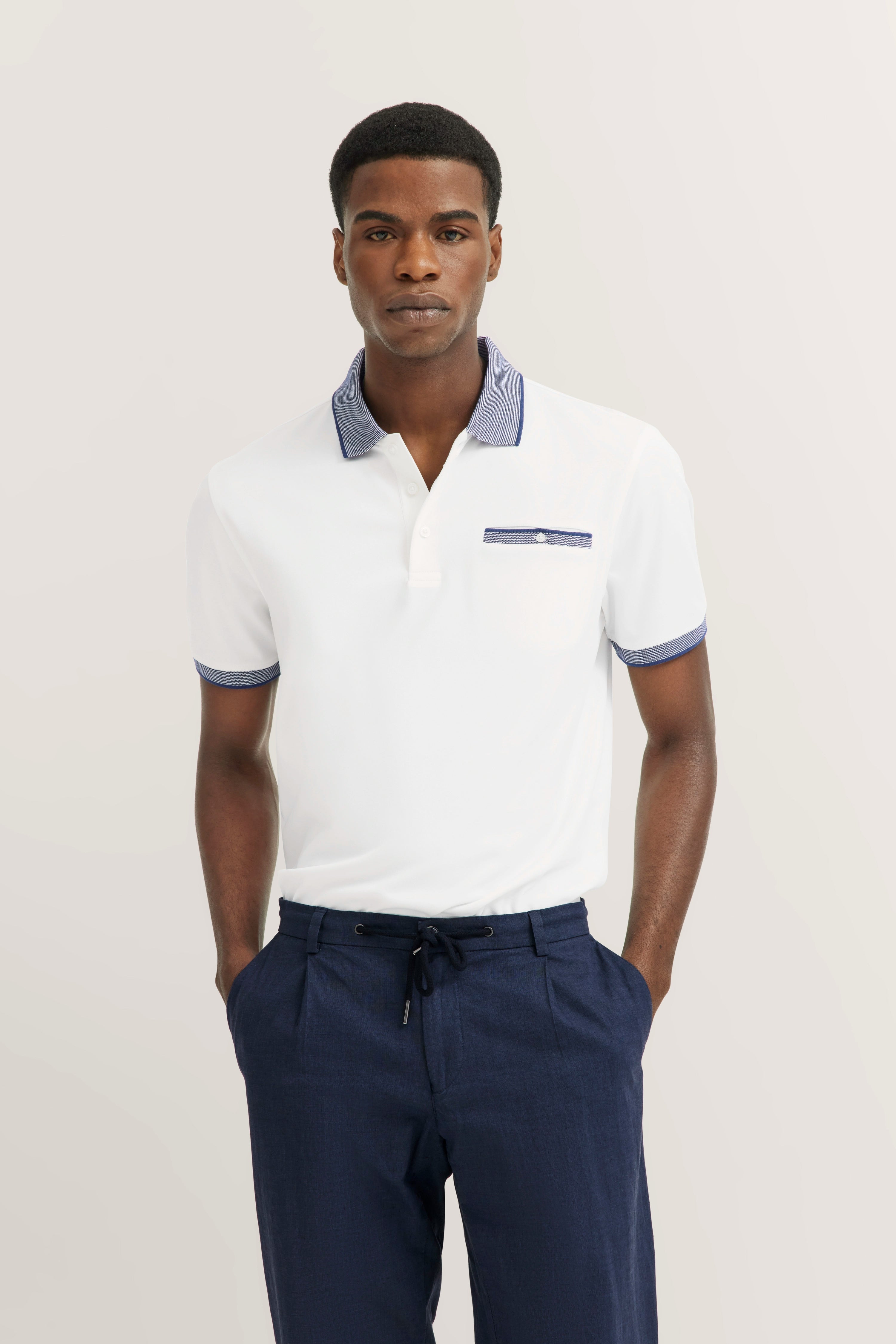 White polo shirt with blue collar, model pose, casual, blue pants. bugatti style.