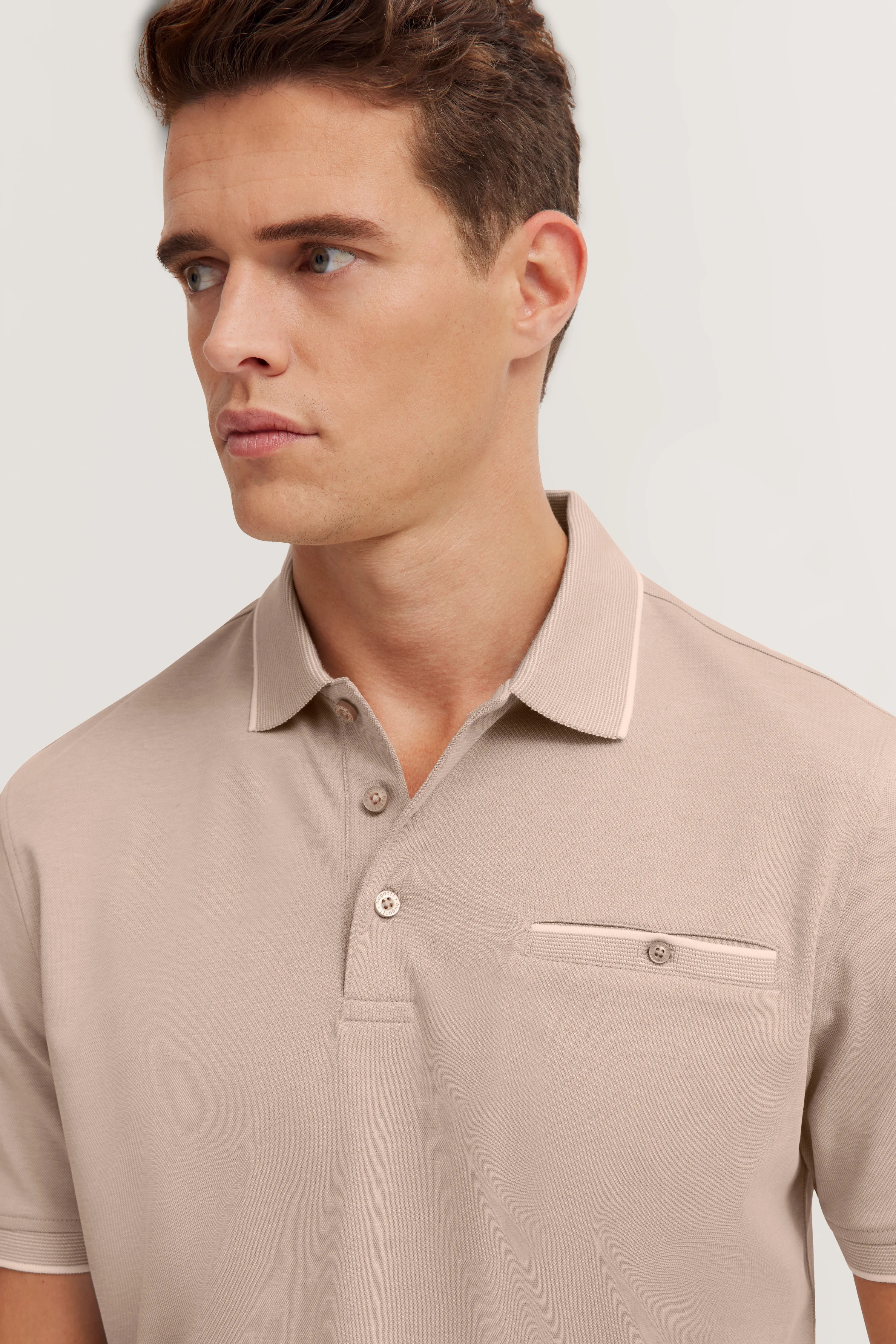 Beige bugatti polo on model, casual pose, half-profile, elegant look.
