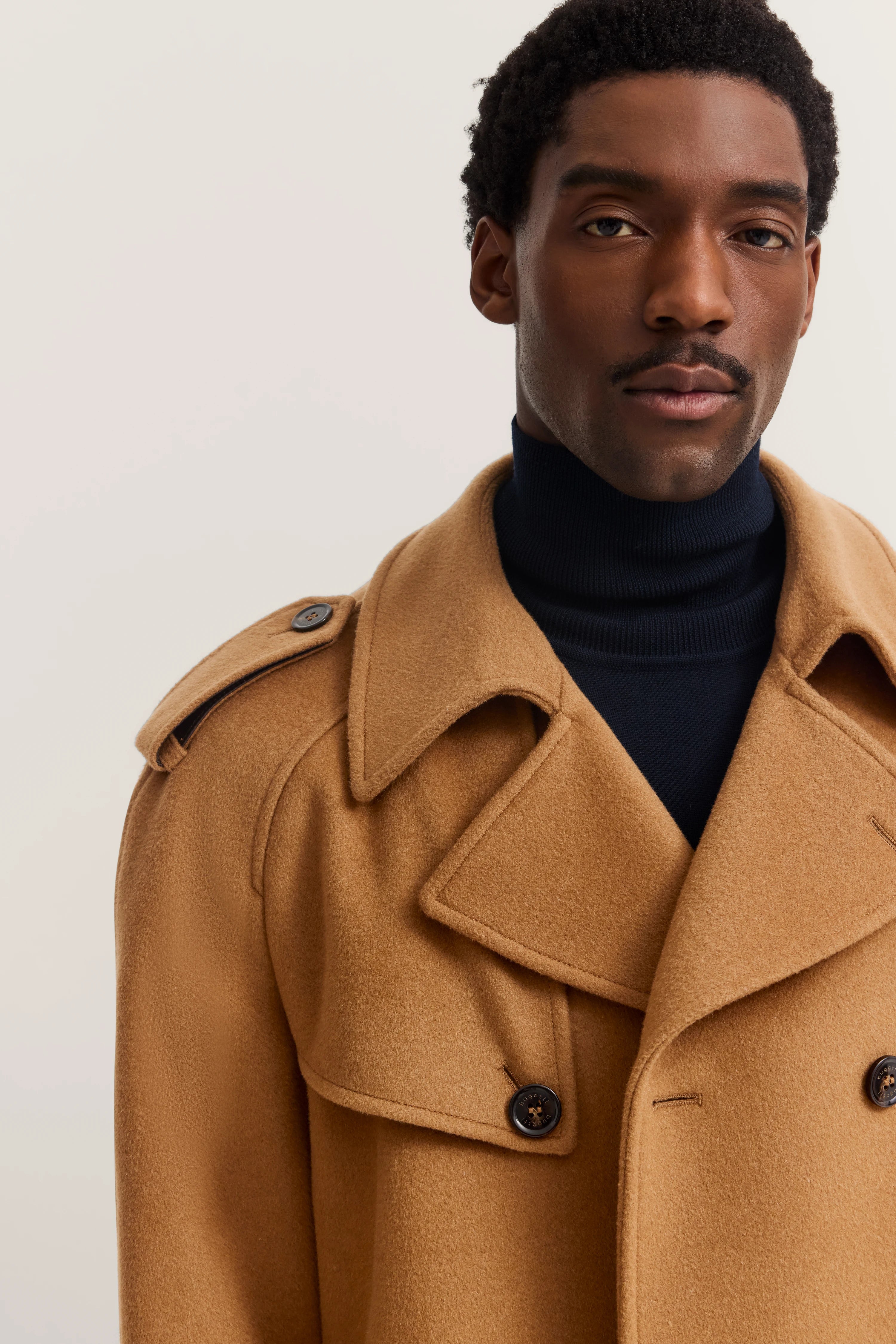 Bust in camel coat by bugatti, paired with black turtleneck. Elegance and timeless beauty.