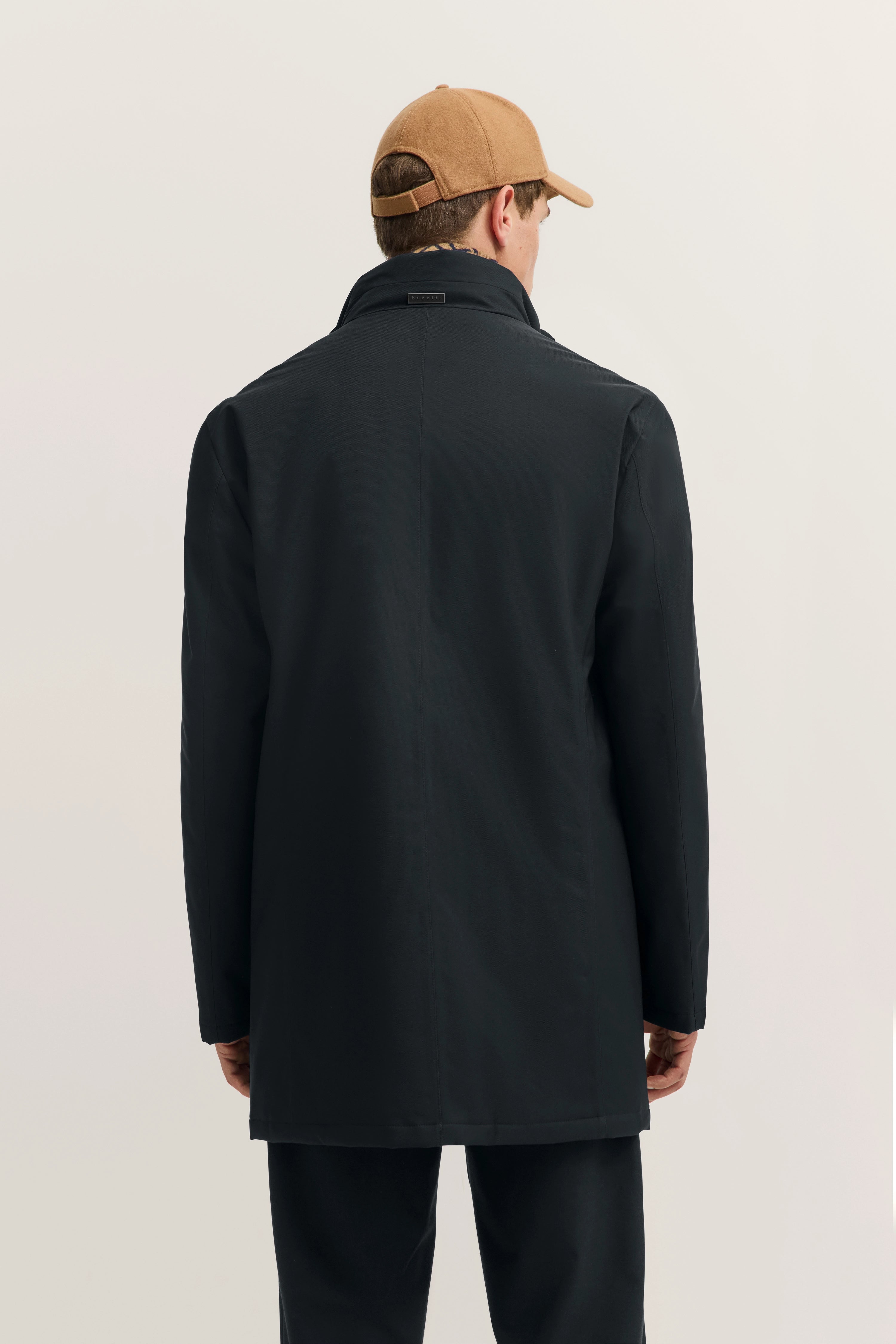 bugatti Mantel in Schwarz, Büstenbild von hinten, lässig mit beige Cap.