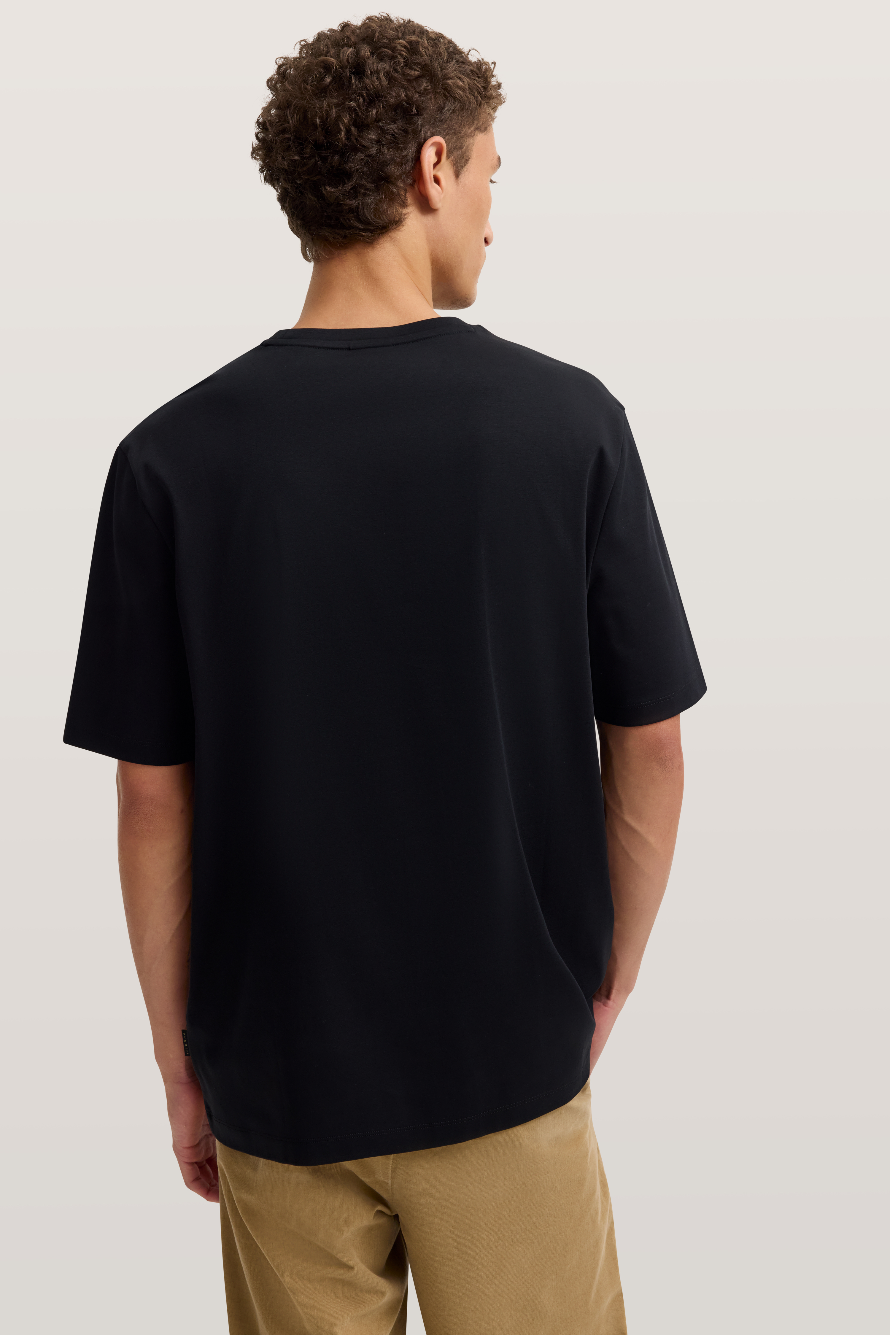 Schwarzes T-Shirt und beige Hose von bugatti, Rückenansicht, legeres Modelbild.