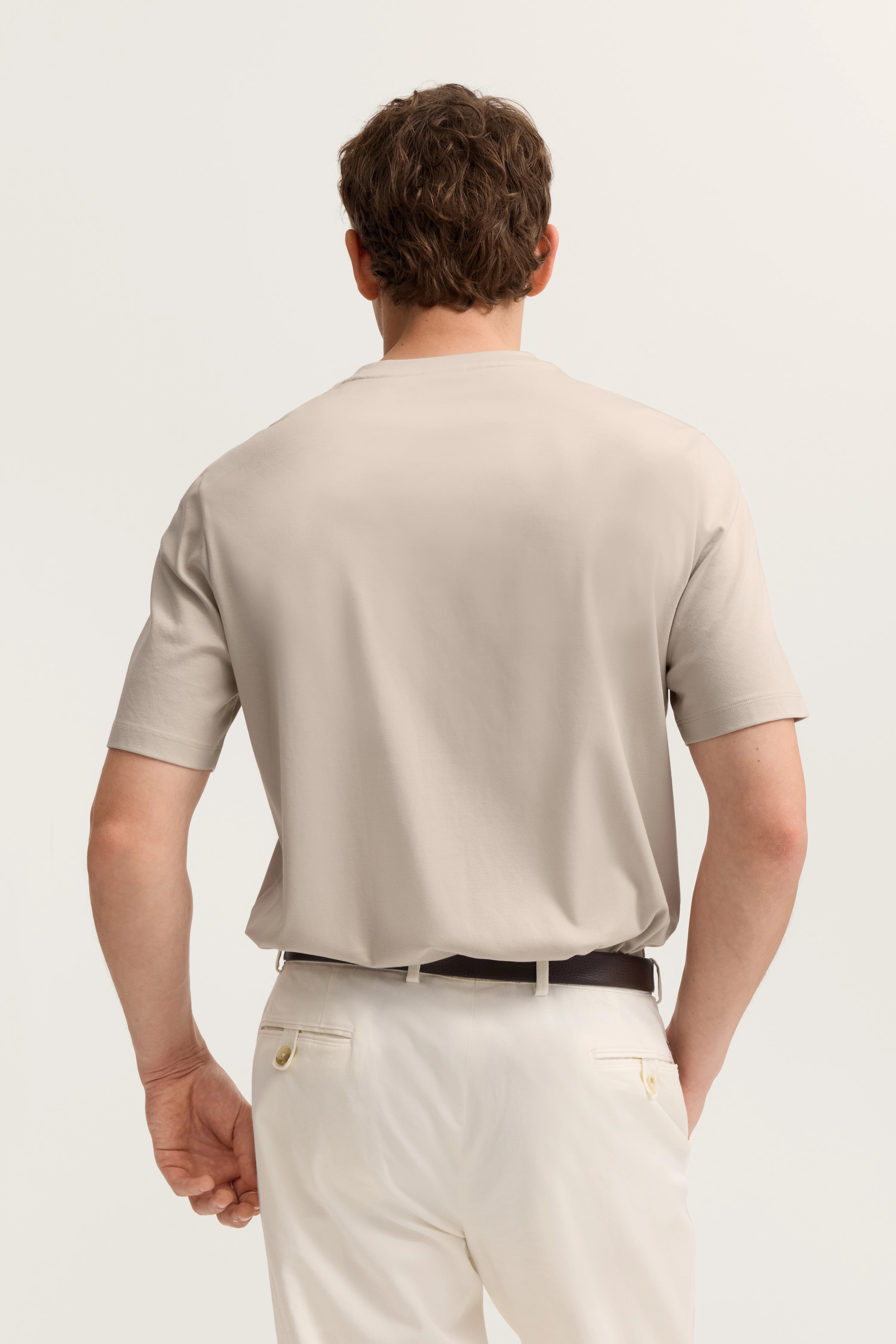Rückansicht-Model im cremefarbenem bugatti T-Shirt und weißen Hosen.