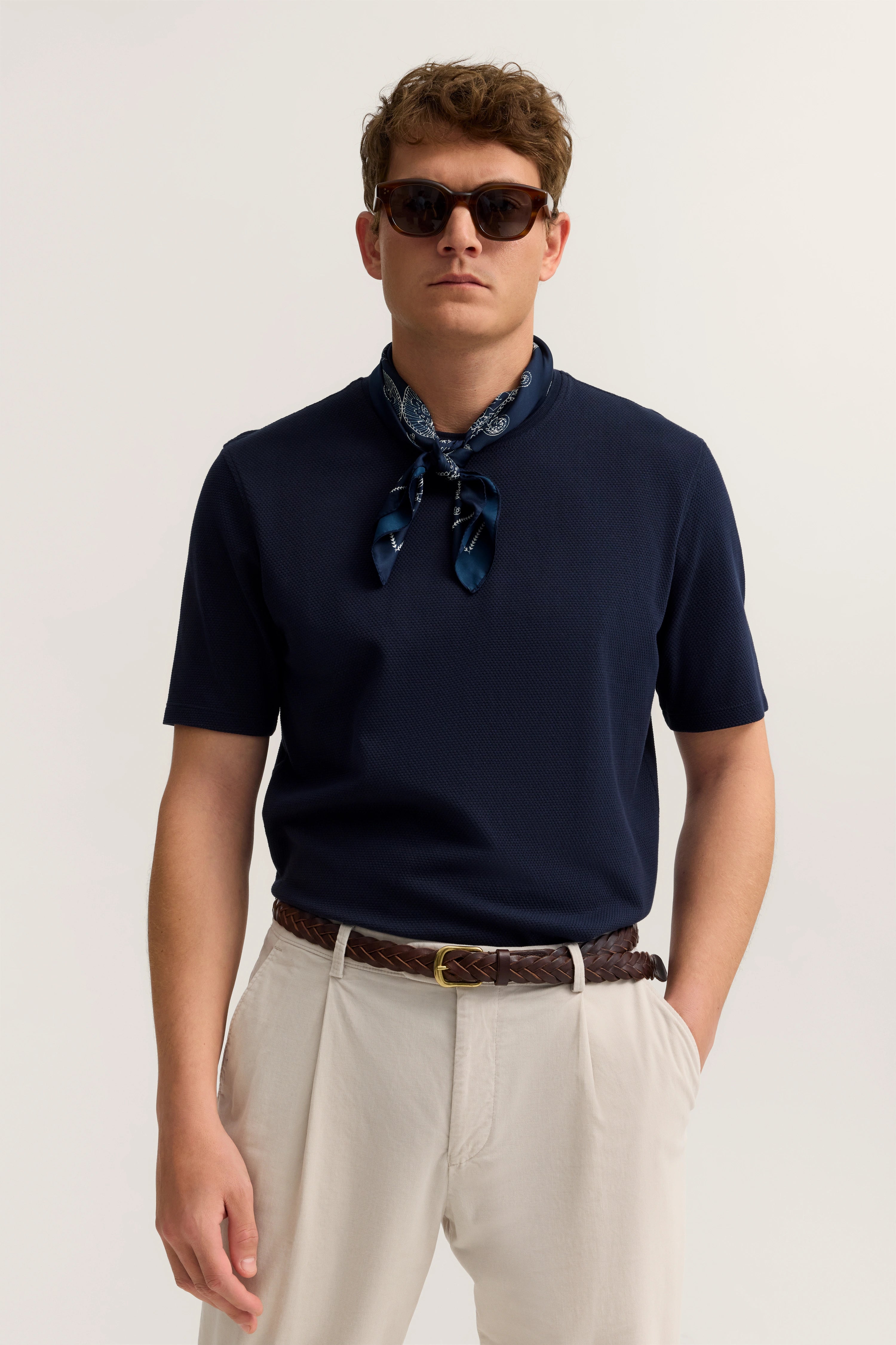 Navy Shirt, beige Pants, brauner Gürtel, blauer Schal, Modelbild, Frontpose, Sonnenbrille, Stil von bugatti.