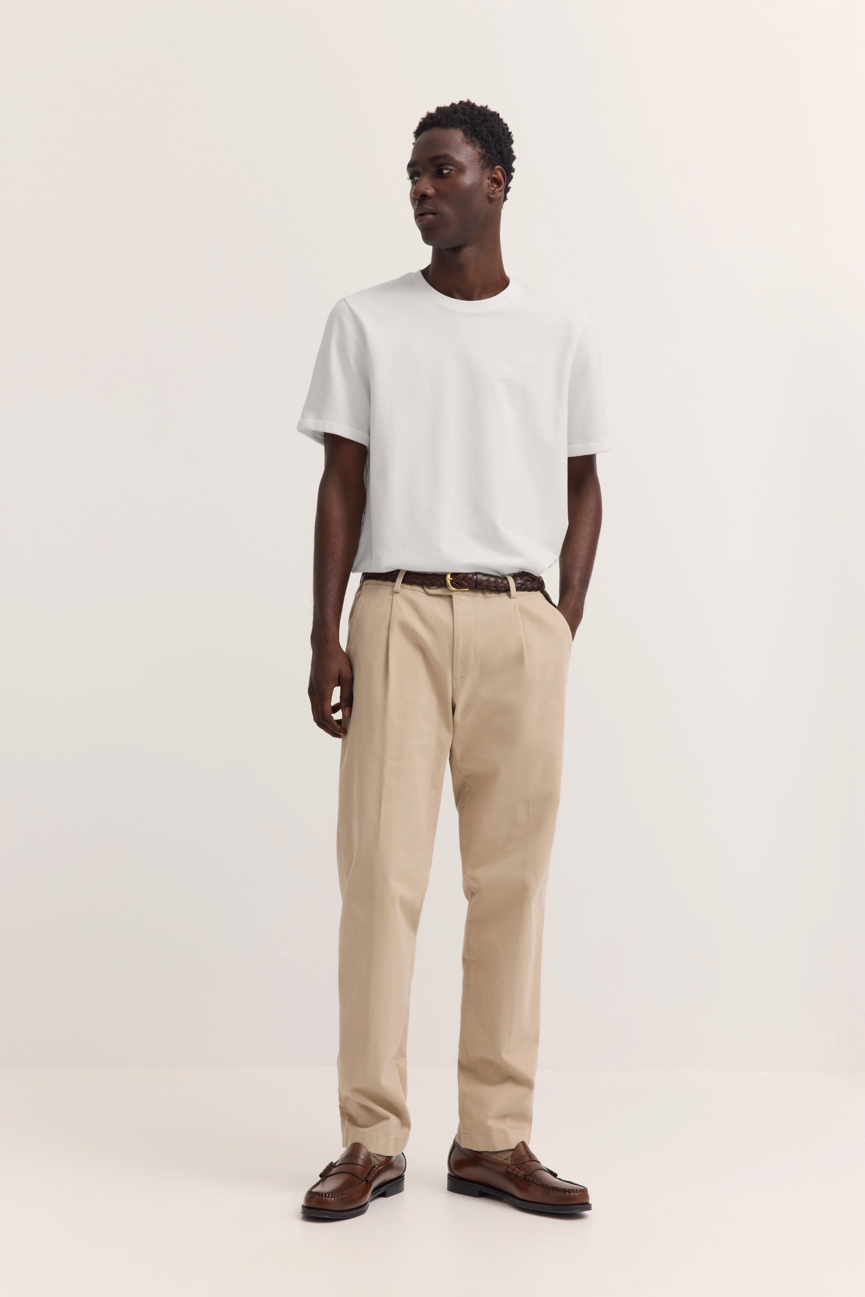 Model in weißem T-Shirt und beigen Hosen, braune Schuhe