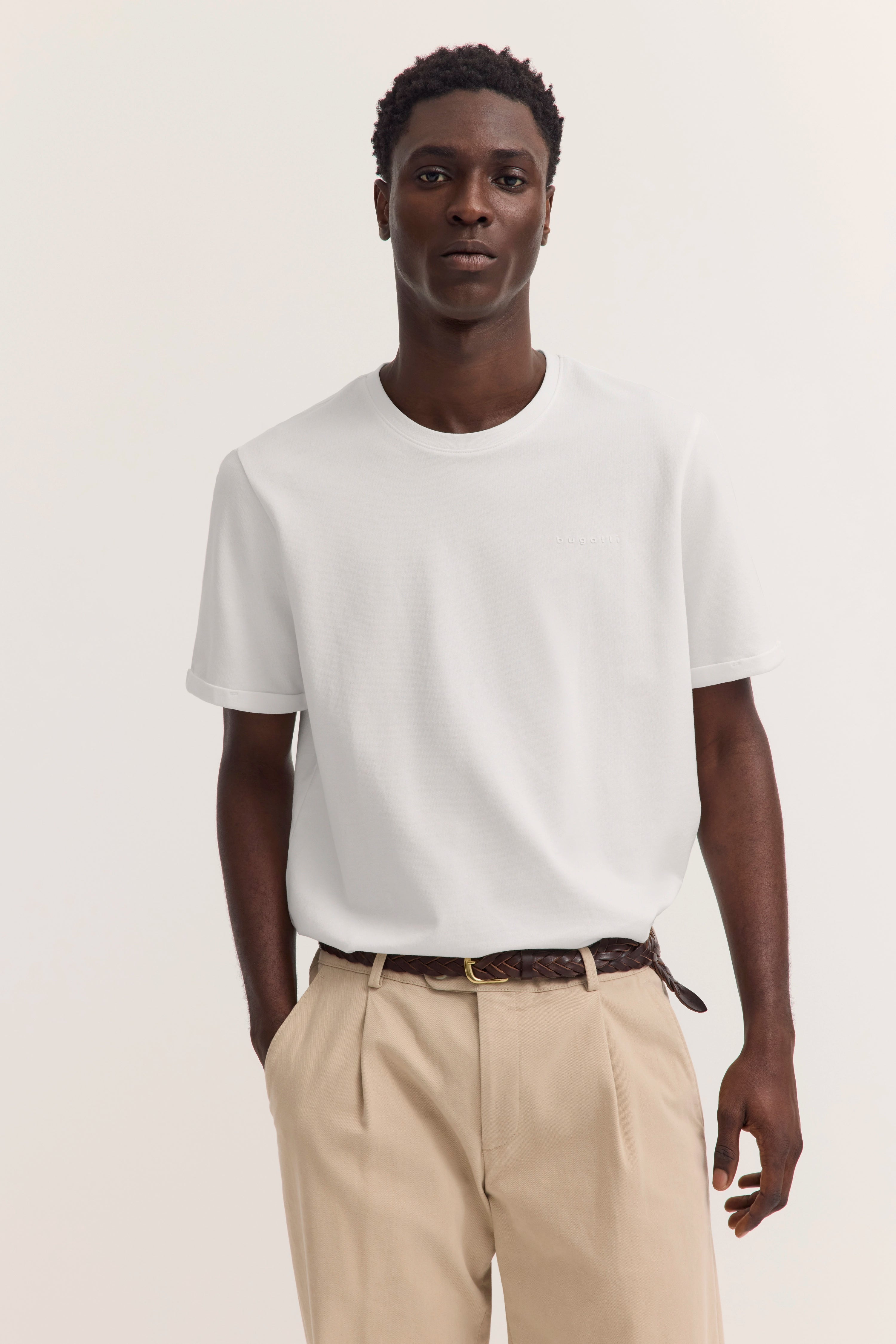 Weißes bugatti T-Shirt und beige Hose, Modelbild, entspanntes Posing.