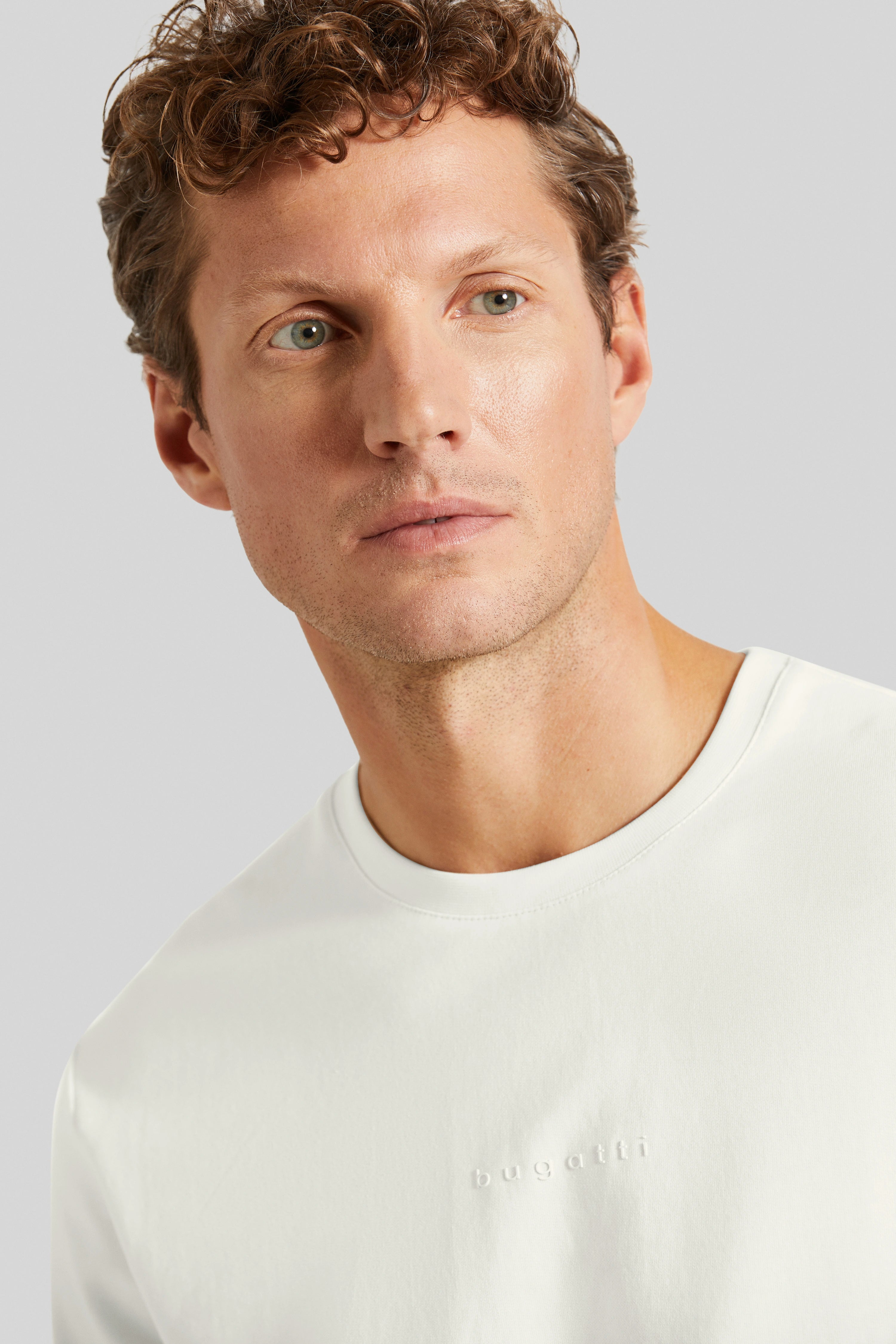 Model wearing white bugatti T-shirt, relaxed pose, focus on upper body.