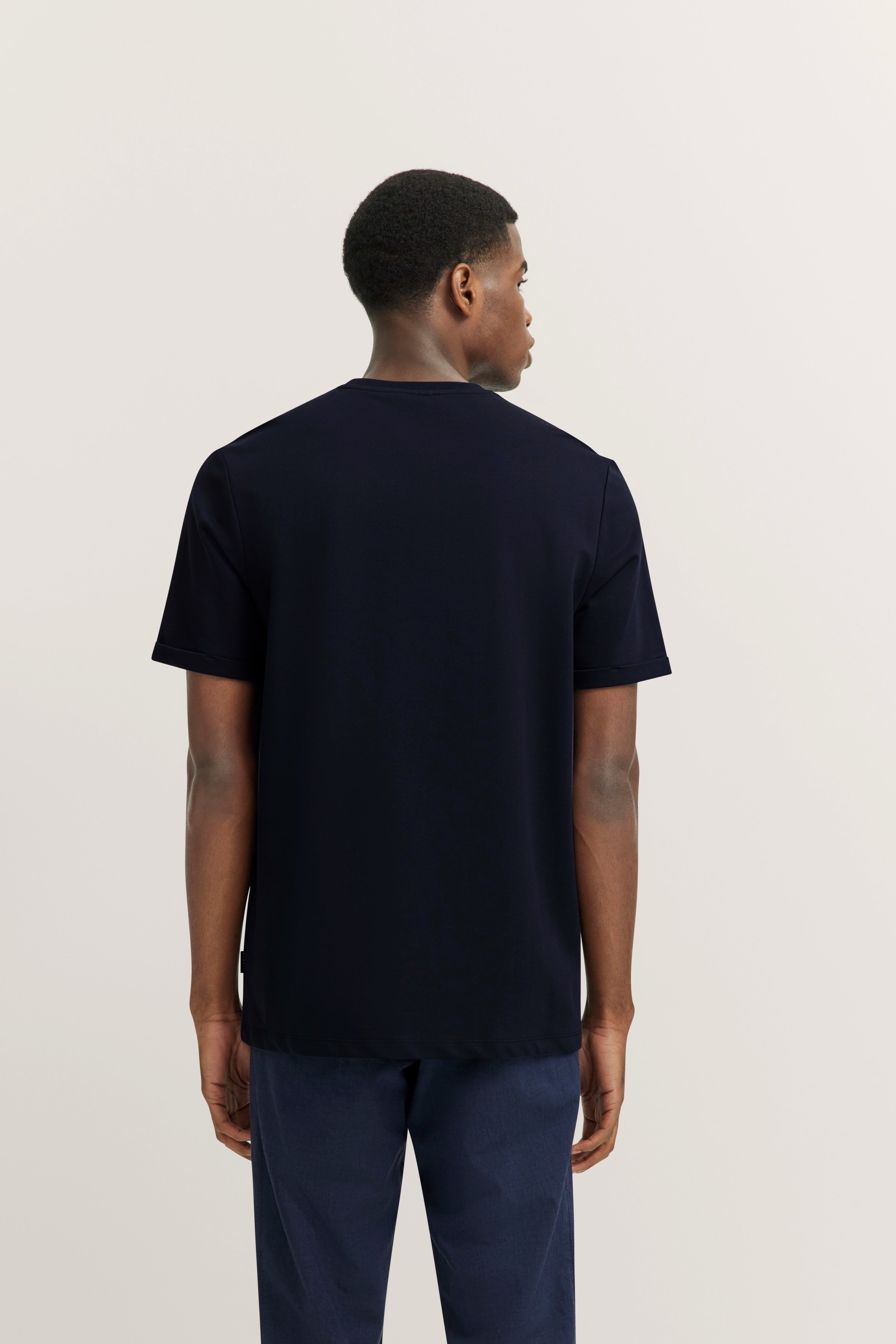 Black bugatti T-shirt and blue pants, model seen from behind.