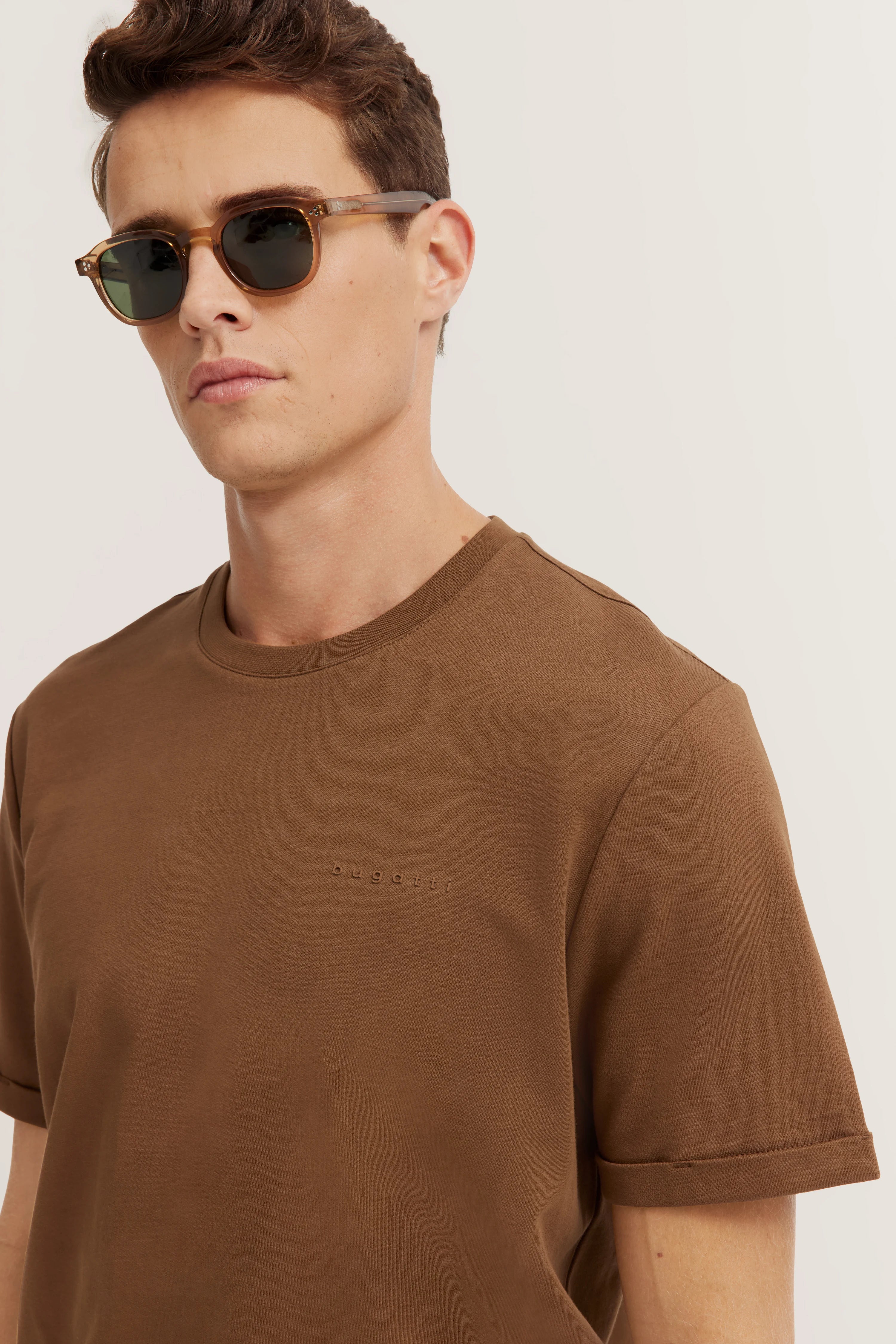 Brown bugatti T-shirt, model posing casually with sunglasses.