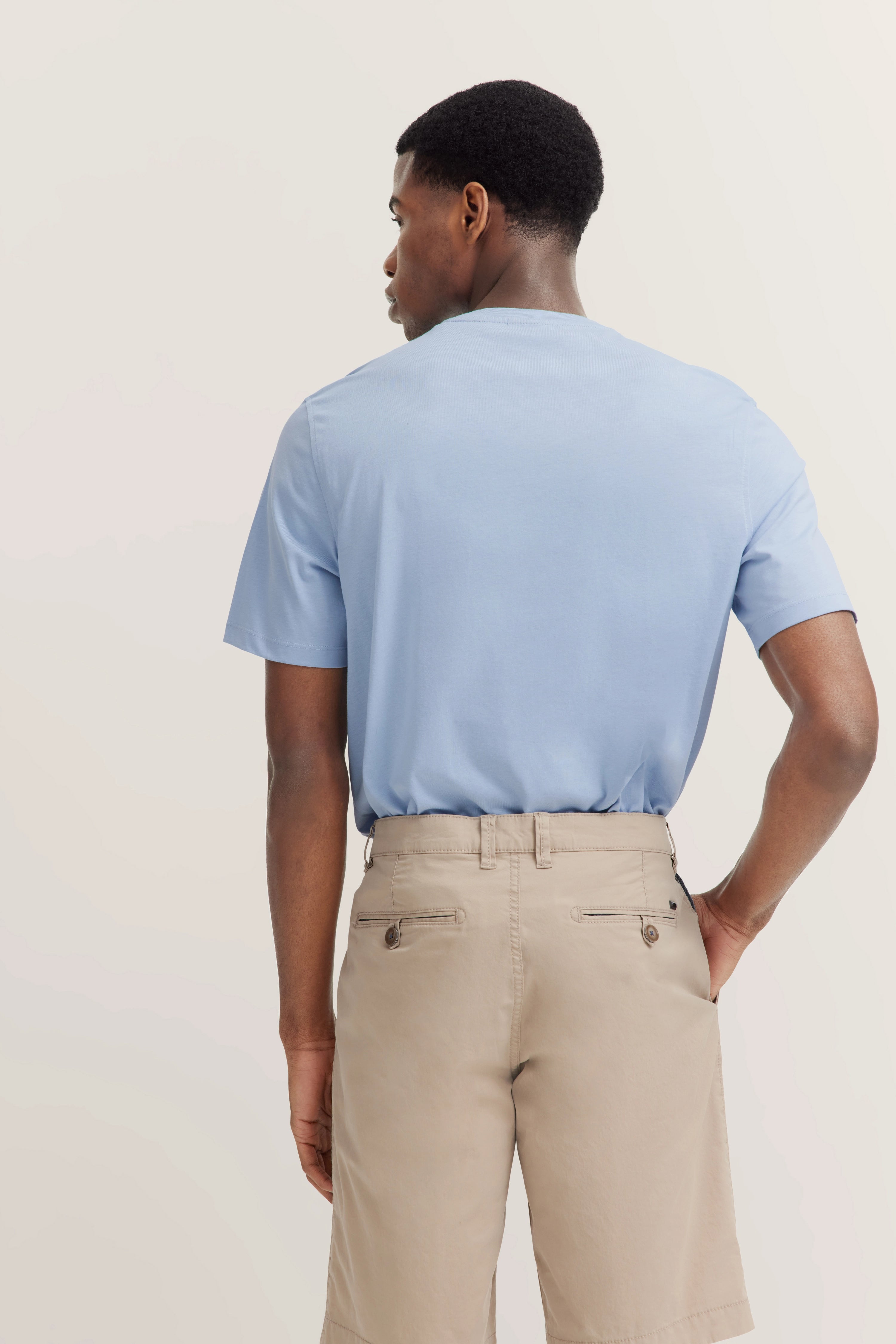 Hellblaues T-Shirt und beige Shorts im legeren Modelbild, Rückenansicht, bugatti Stil.