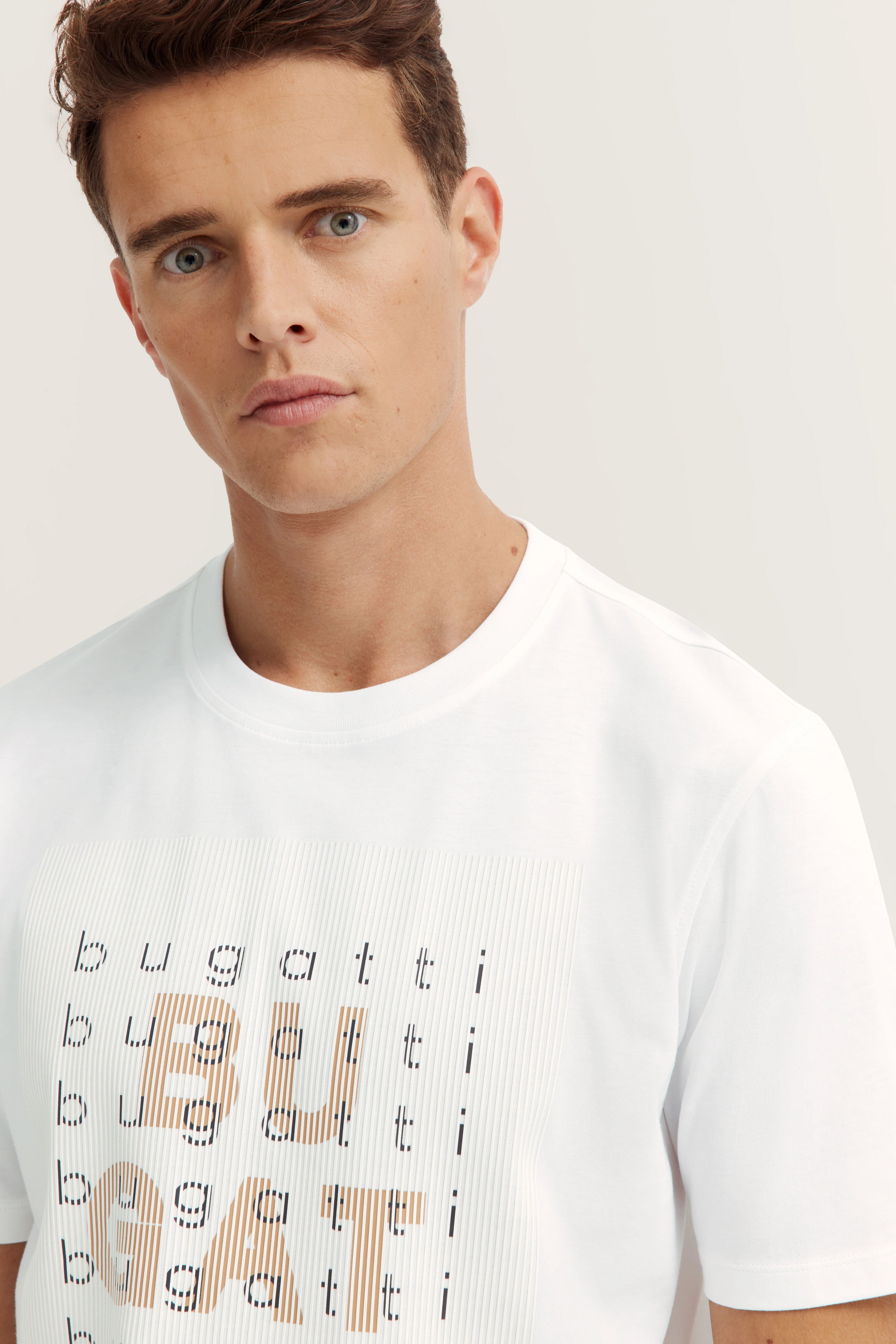 Model in weißem bugatti T-Shirt mit Logo-Print, frontal, entspannte Haltung.