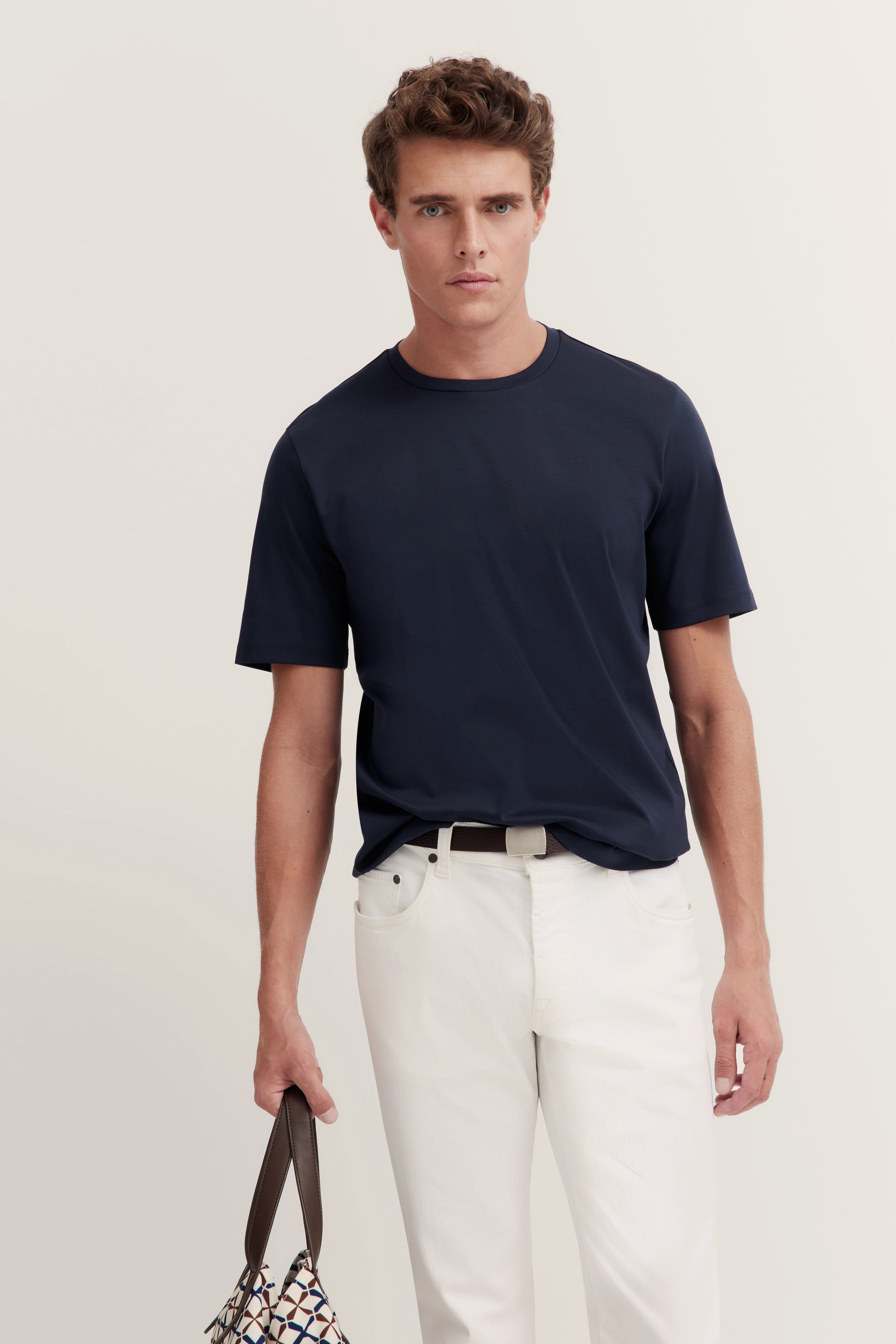 Dark blue T-shirt with white pants, model standing, bugatti style.