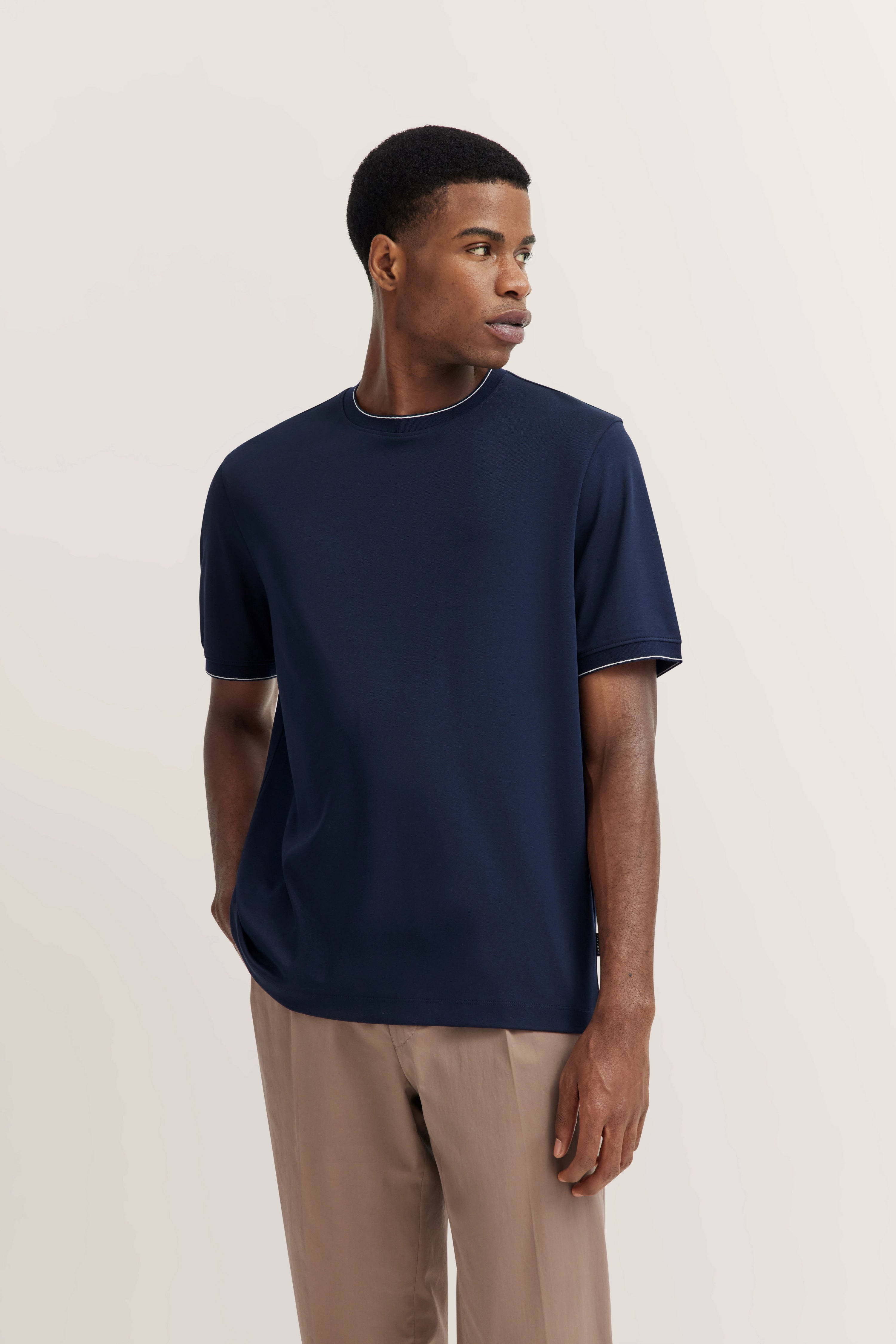 Dark blue T-shirt and beige pants, casual model image, relaxed pose.