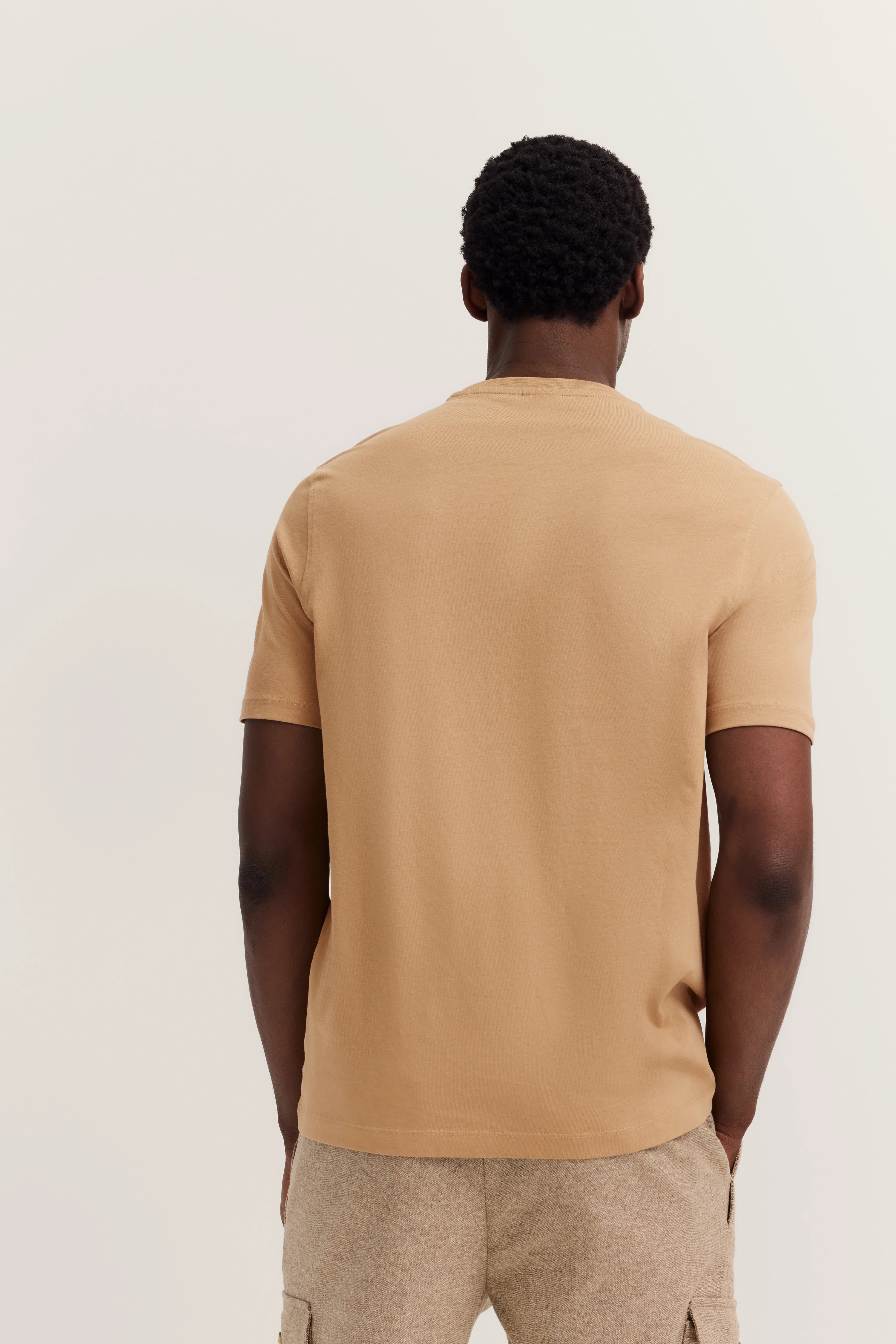 Beigefarbenes T-Shirt und Hose, Rückansicht, legerer Look, Modelbild.