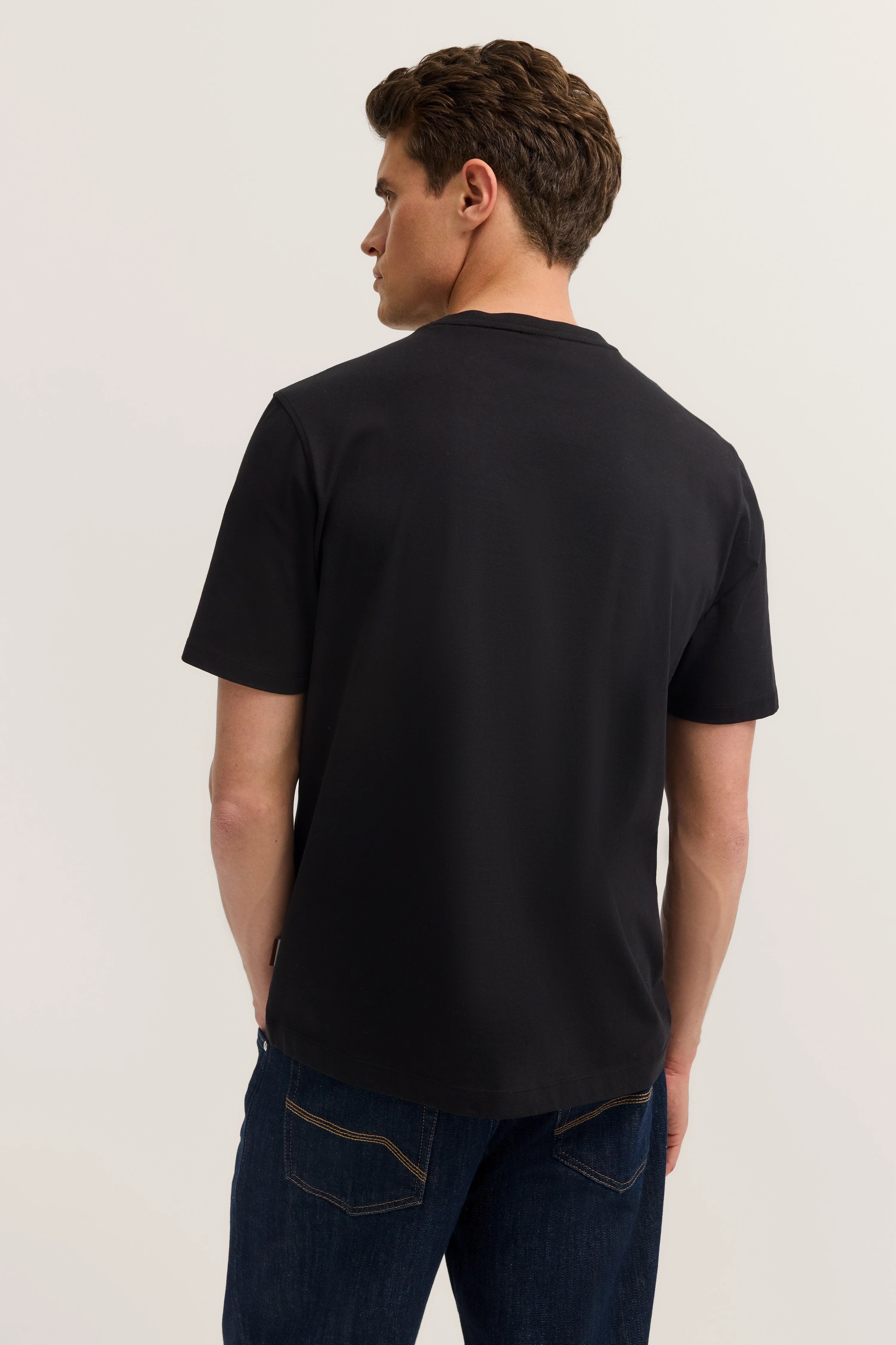 Schwarzes bugatti T-Shirt, Rückansicht, lässiges Model, mit Jeans kombiniert.