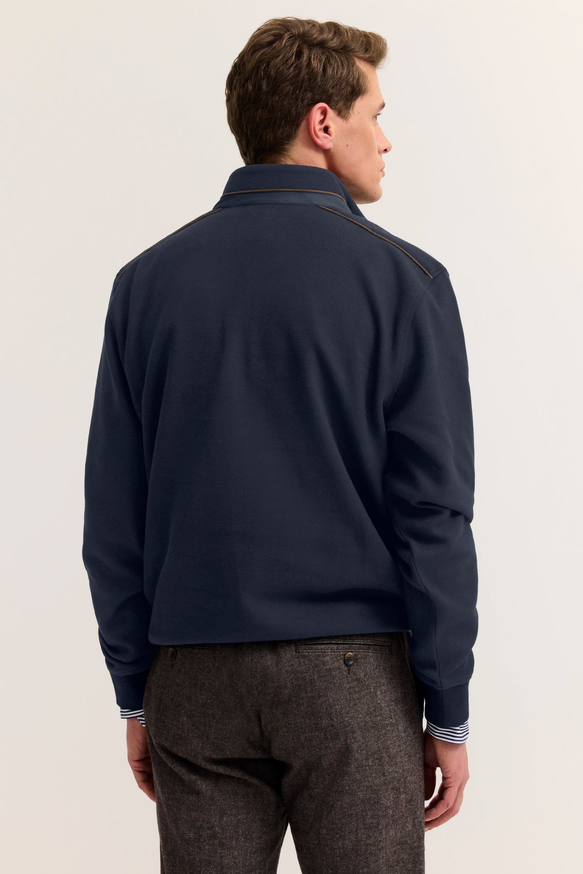 Bugatti Herrenoutfit, Navy-Jacke, braune Hose, Modelbild von hinten, lässige Pose.
