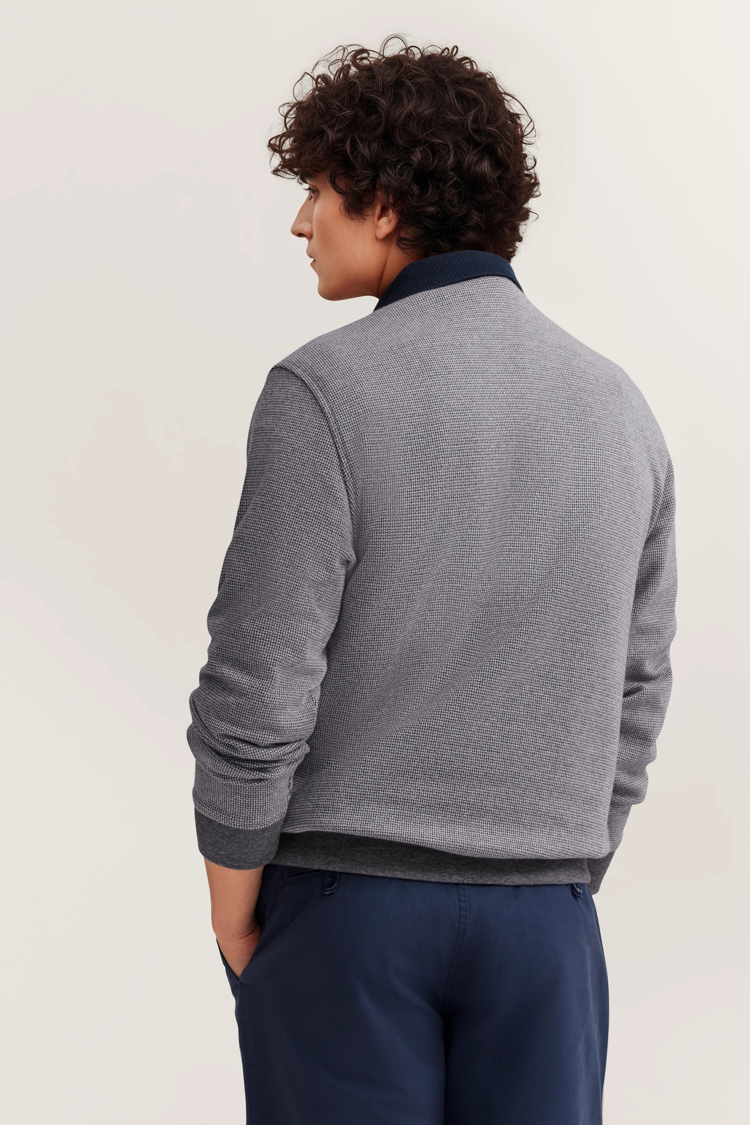 Graue bugatti-Jacke und blaue Hose, legeres Modelbild, Rückenansicht, entspannte Haltung.