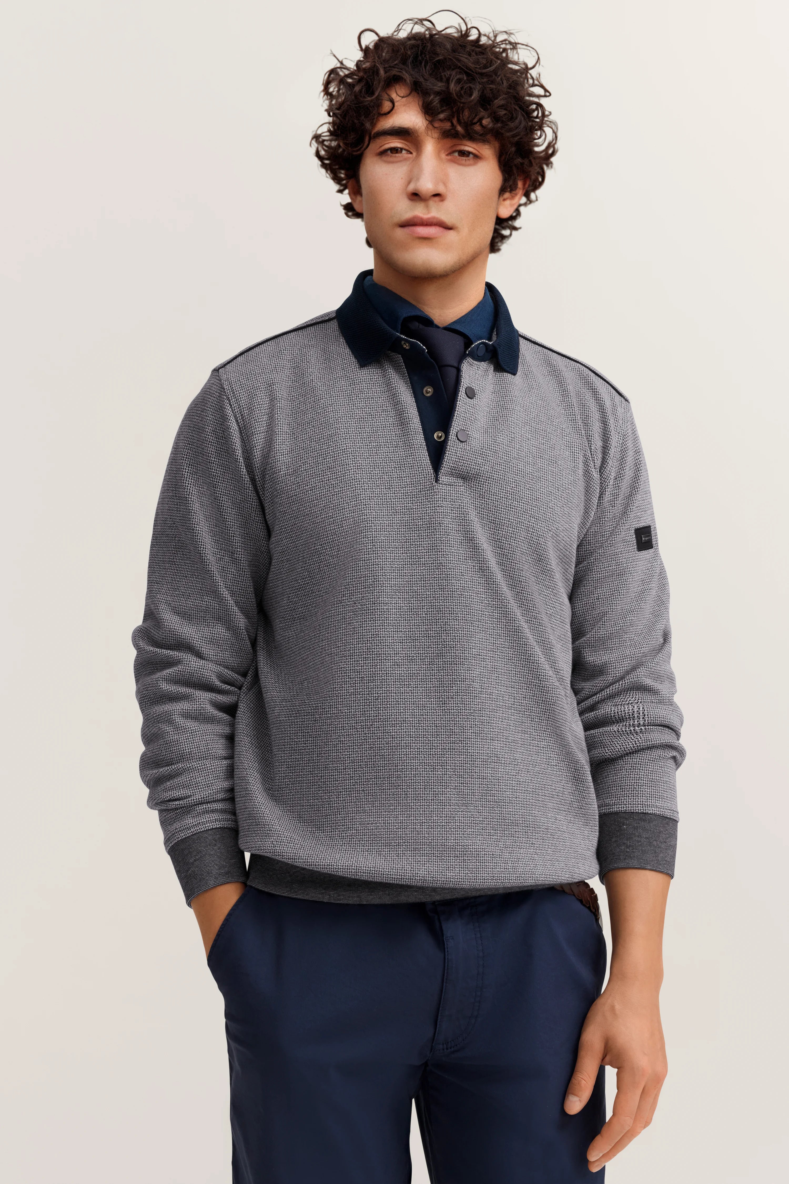 Grauer Pullover, dunkelblaue Hose, Modelbild, lässige Pose, Stil von bugatti.