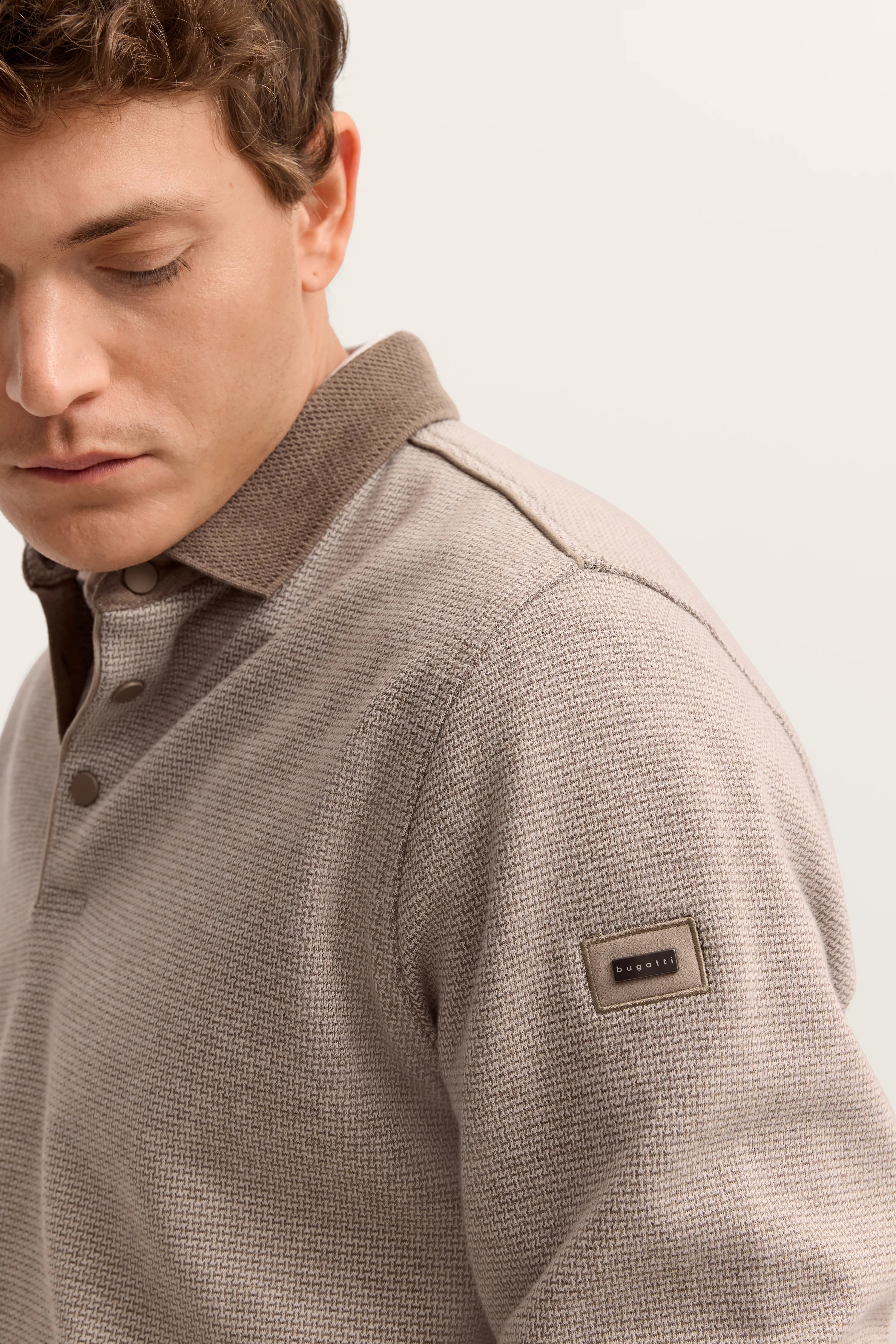 bugatti Herrenmodell in beige Strickpolo mit braunem Kragen, Detailansicht, legeres Posing.