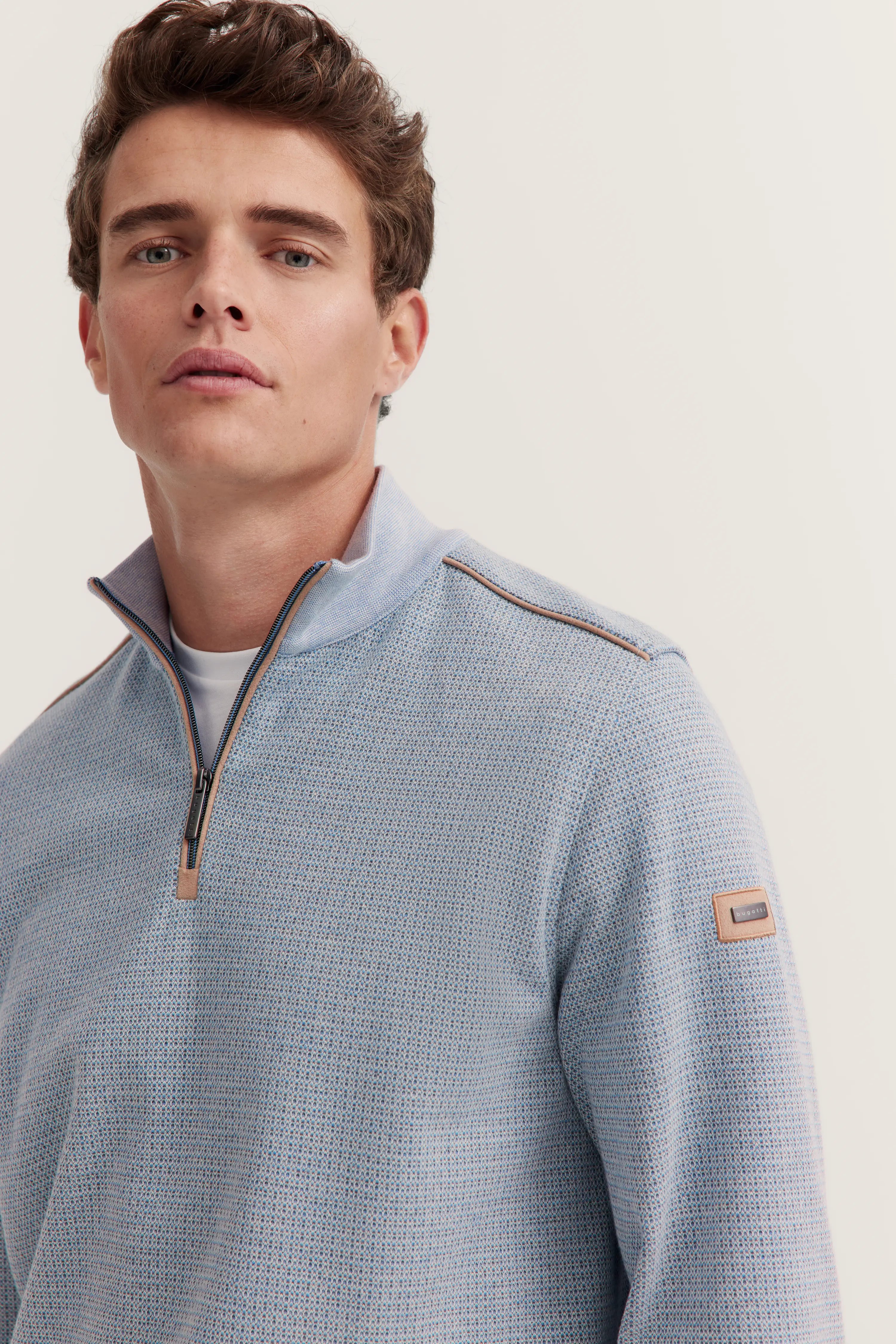 Model trägt hellblauen bugatti Pullover mit Reißverschluss, dezentes Muster, leger, halbnahes Porträt.