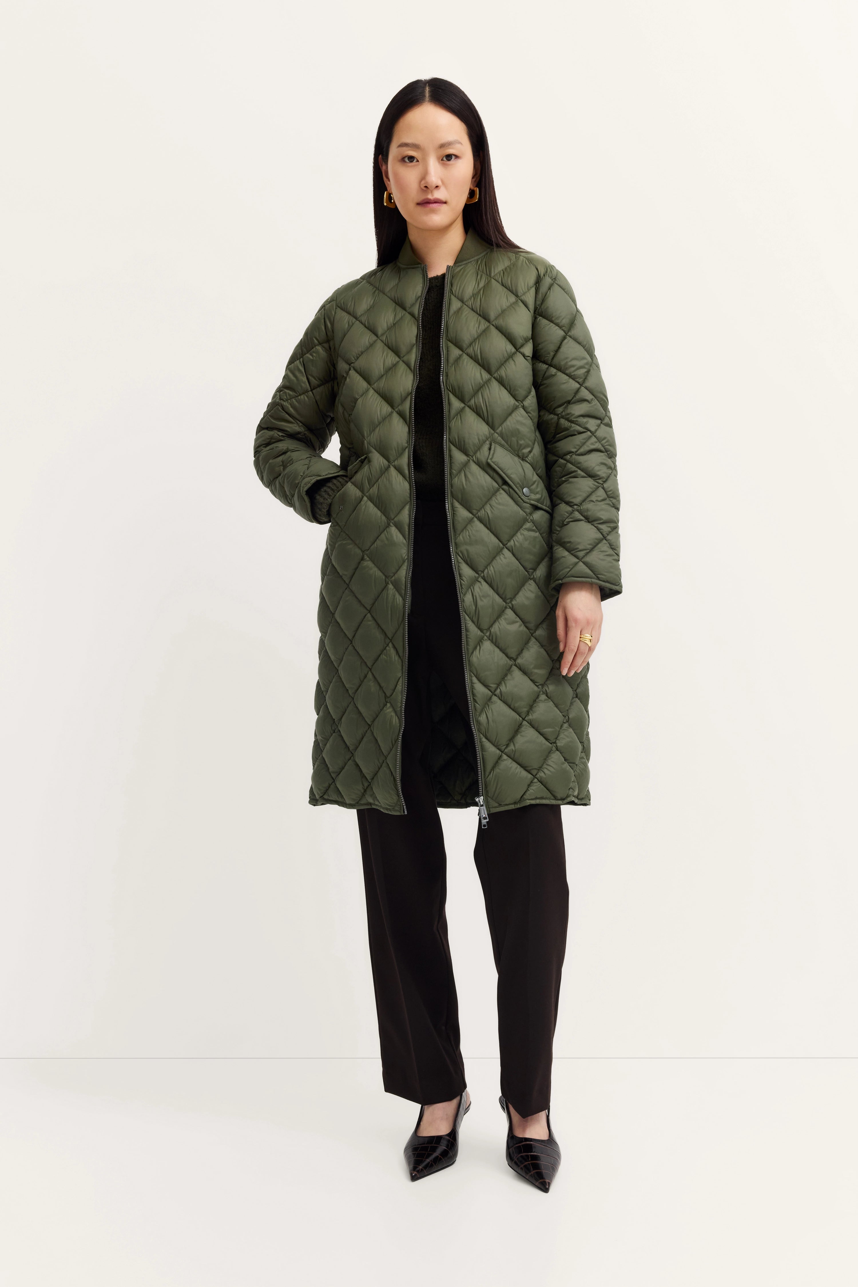 Green quilted coat with black pants, model standing, bugatti style.