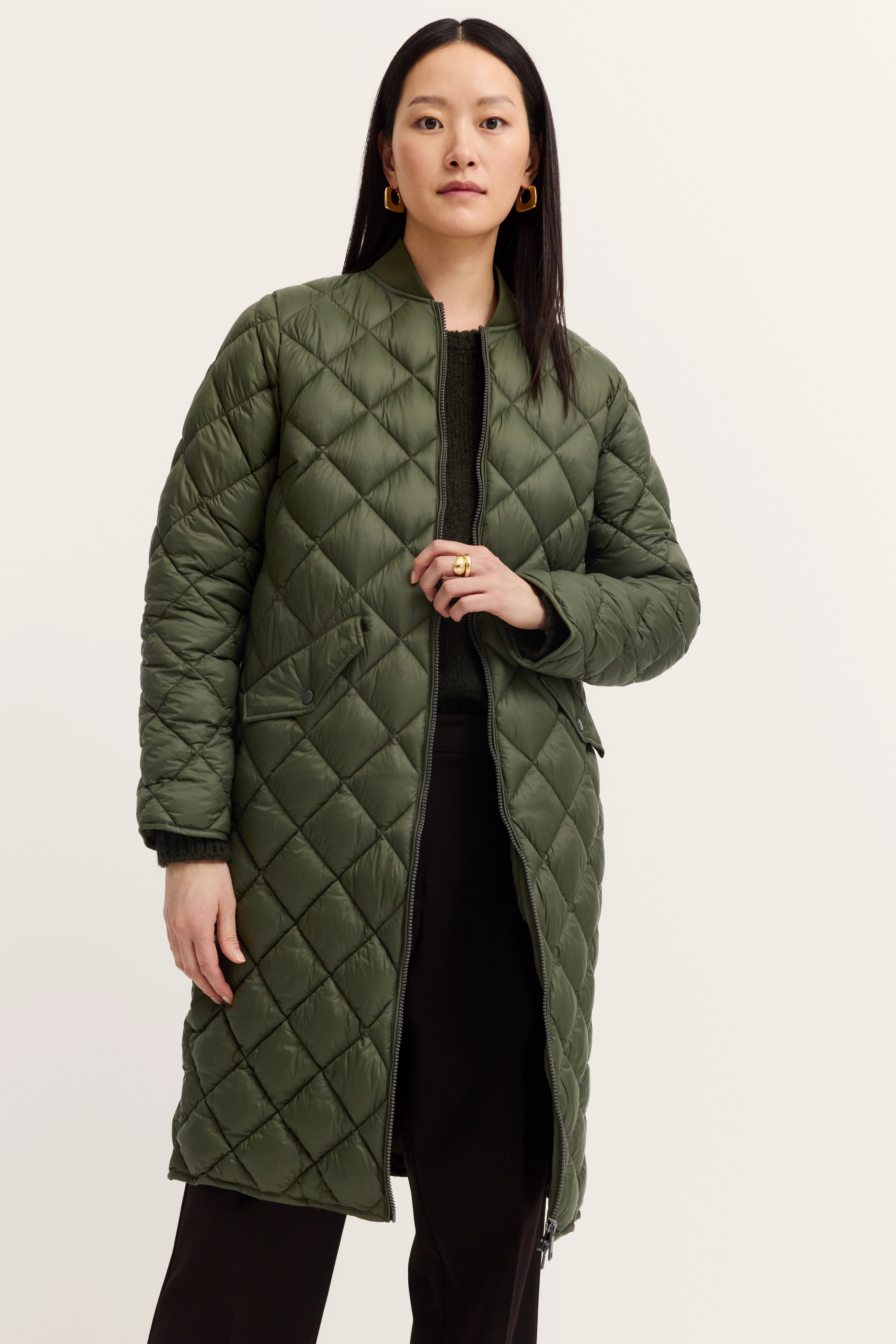 Model in olive quilted jacket, black outfit, casual pose, bugatti style and elegance.