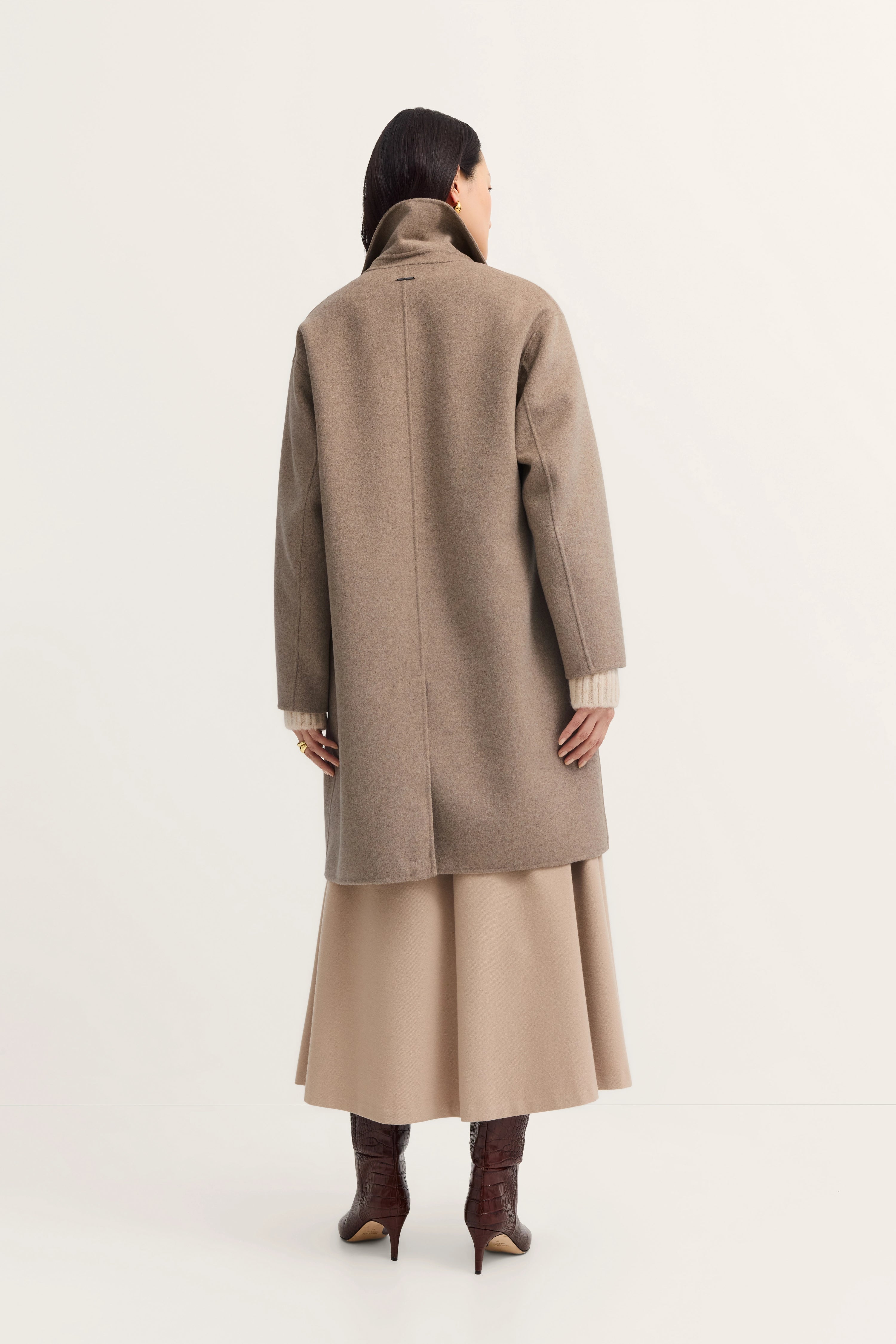 Beiges bugatti Outfit mit Mantel, Rock in A-Linie und braunen Stiefeln, Rückansicht Model casual.