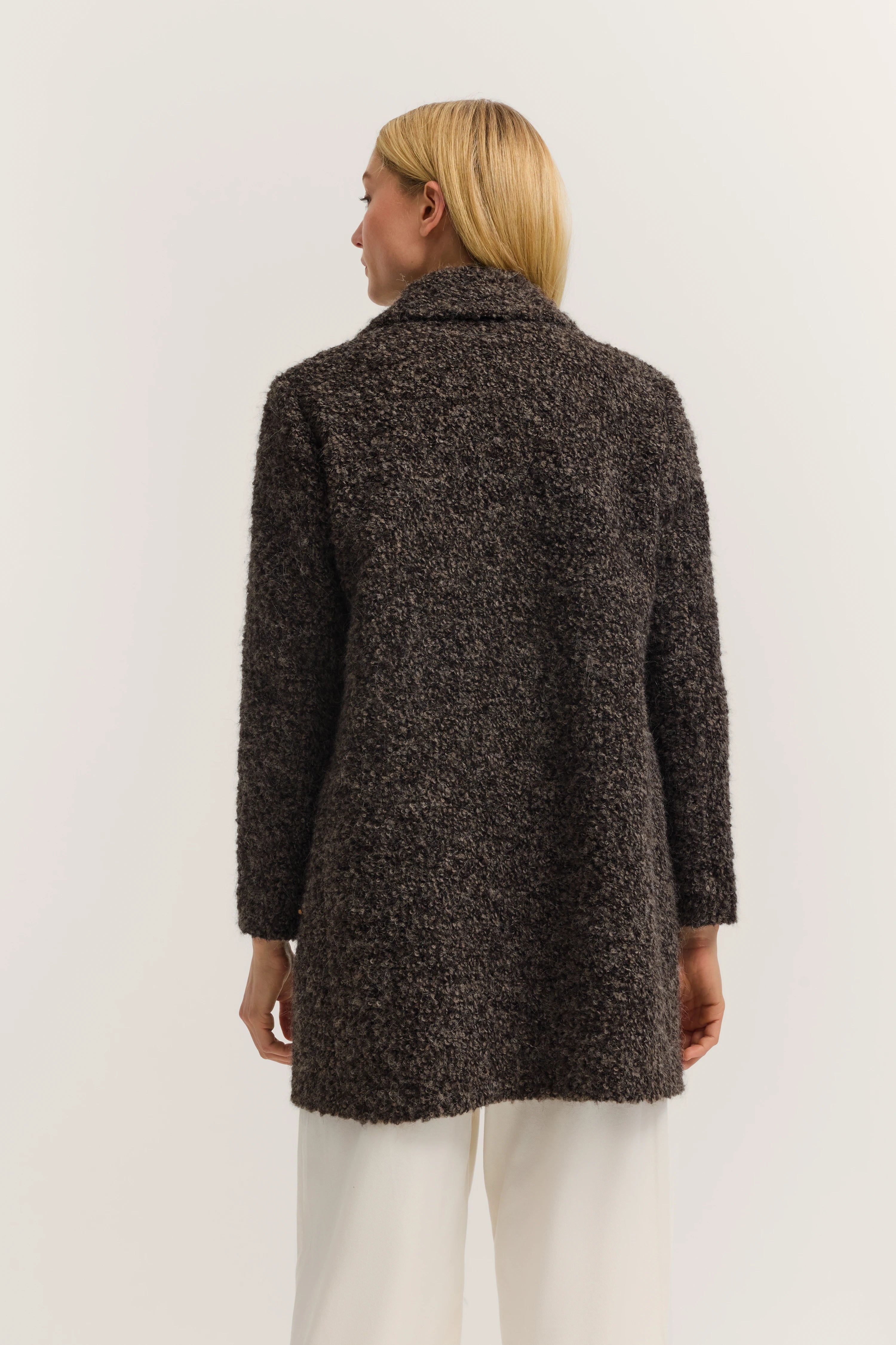 Bruine bouclé-jas van bugatti, model van achteren, gecombineerd met witte broek.