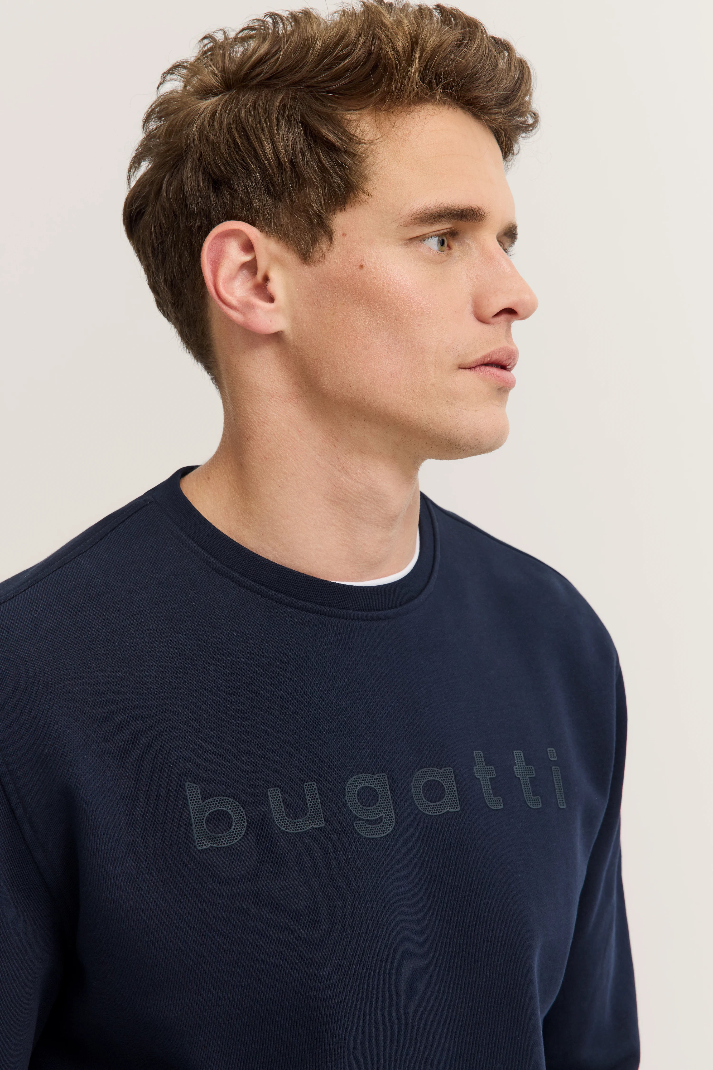 Navy bugatti sweatshirt, model side profile, relaxed pose.