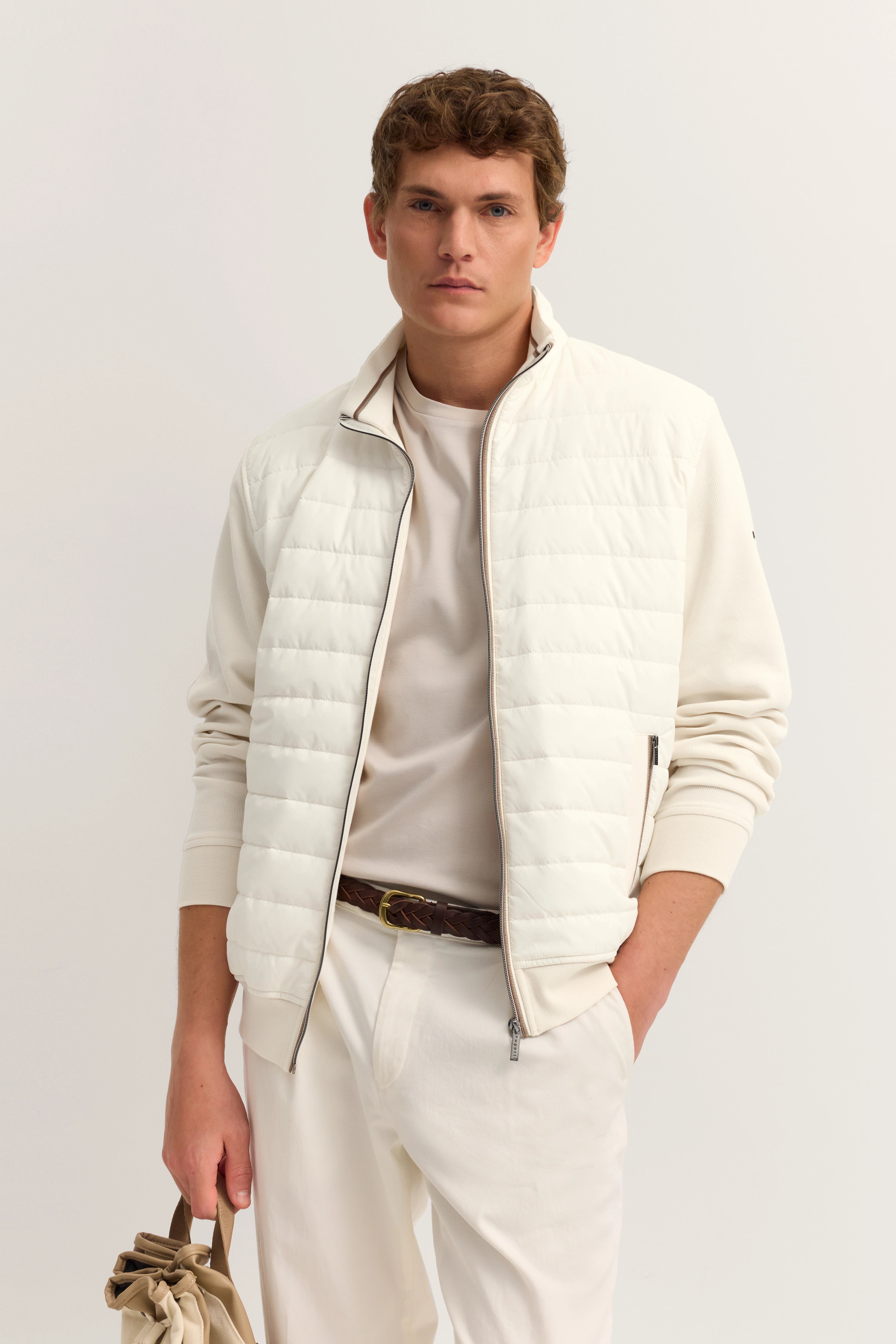 Weißes bugatti Outfit mit Steppjacke, T-Shirt und Hose. Modelbild, entspannte Haltung.